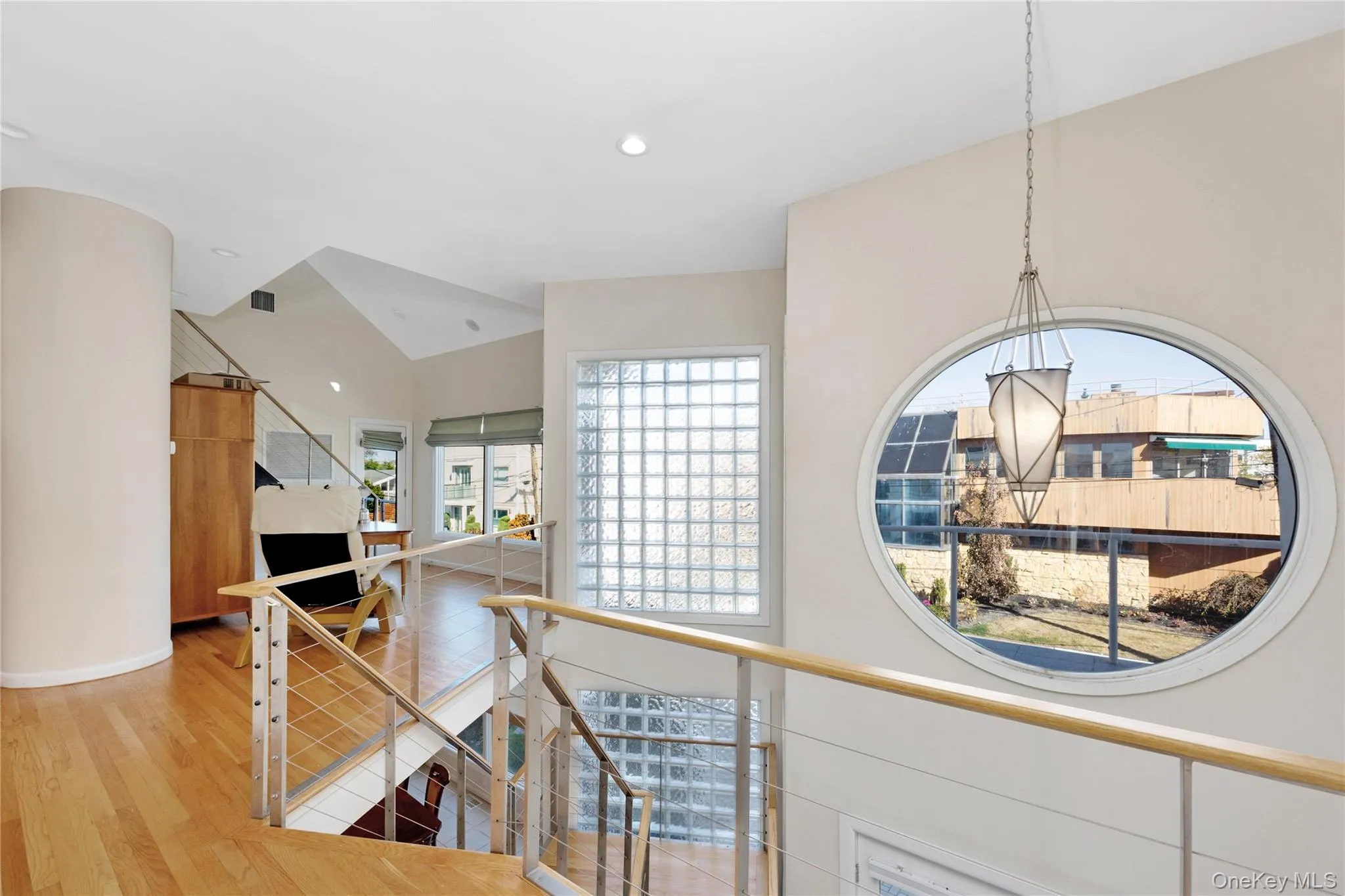 Hall featuring lofted ceiling, recessed lighting, wood finished floors, and an upstairs landing Hall featuring lofted ceiling, recessed lighting, wood finished floors, and an upstairs landing