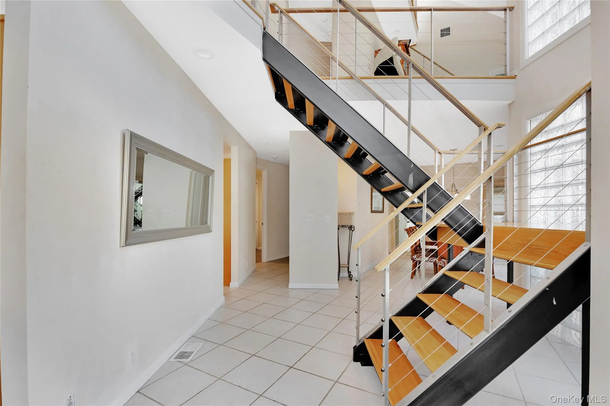 Stairway with visible vents, a high ceiling, baseboards, and tile patterned floors Stairway with visible vents, a high ceiling, baseboards, and tile patterned floors