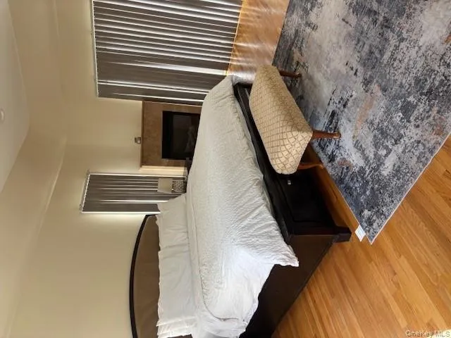 Bedroom featuring light wood-style floors and a tiled fireplace Bedroom featuring light wood-style floors and a tiled fireplace