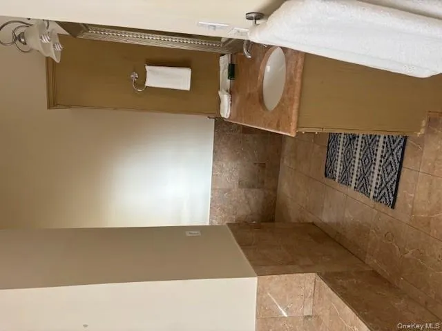 Bathroom with vanity, tile walls, a wainscoted wall, and light tile patterned floors Bathroom with vanity, tile walls, a wainscoted wall, and light tile patterned floors