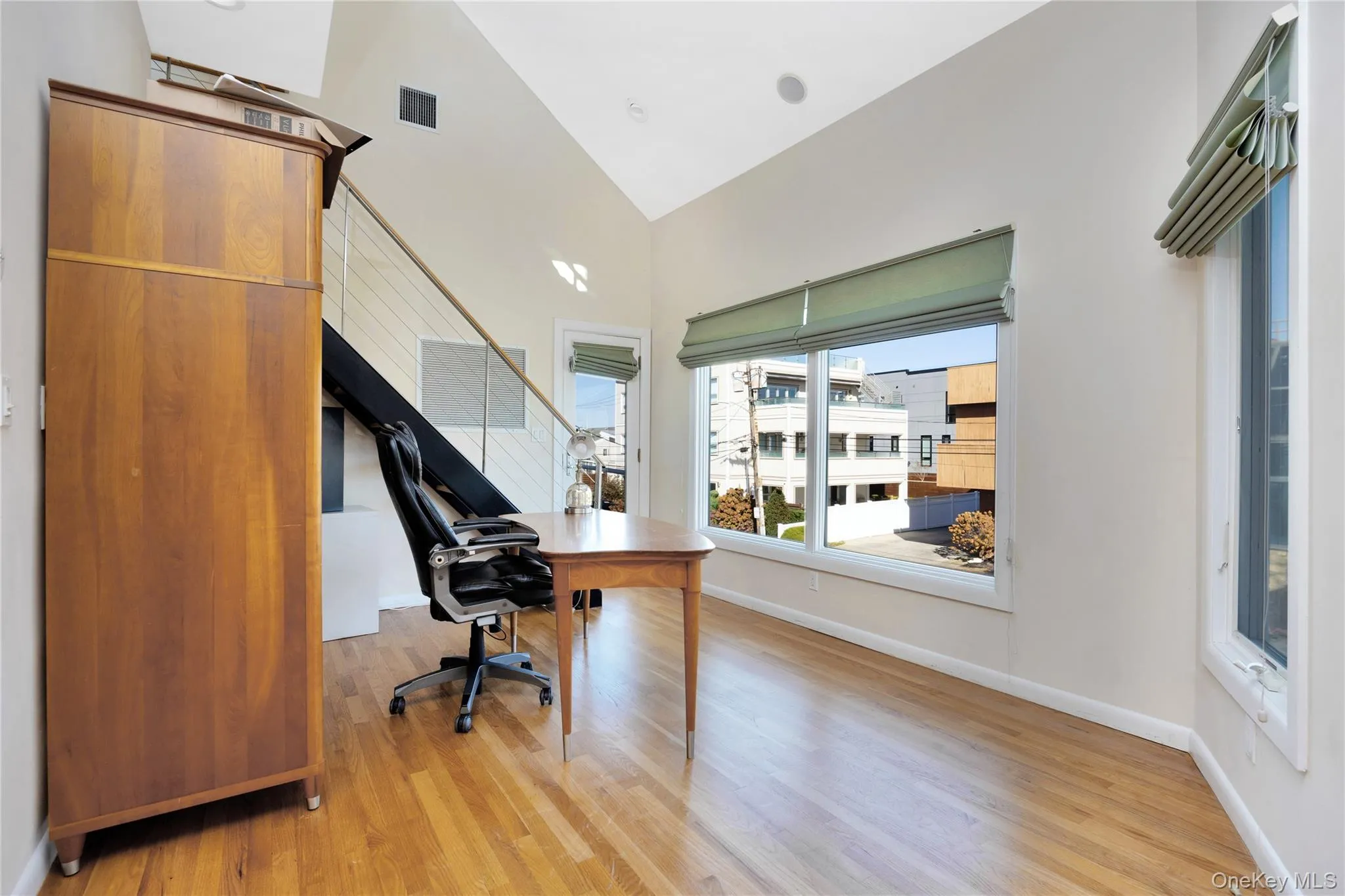 Office with light wood-style floors, visible vents, high vaulted ceiling, and baseboards Office with light wood-style floors, visible vents, high vaulted ceiling, and baseboards