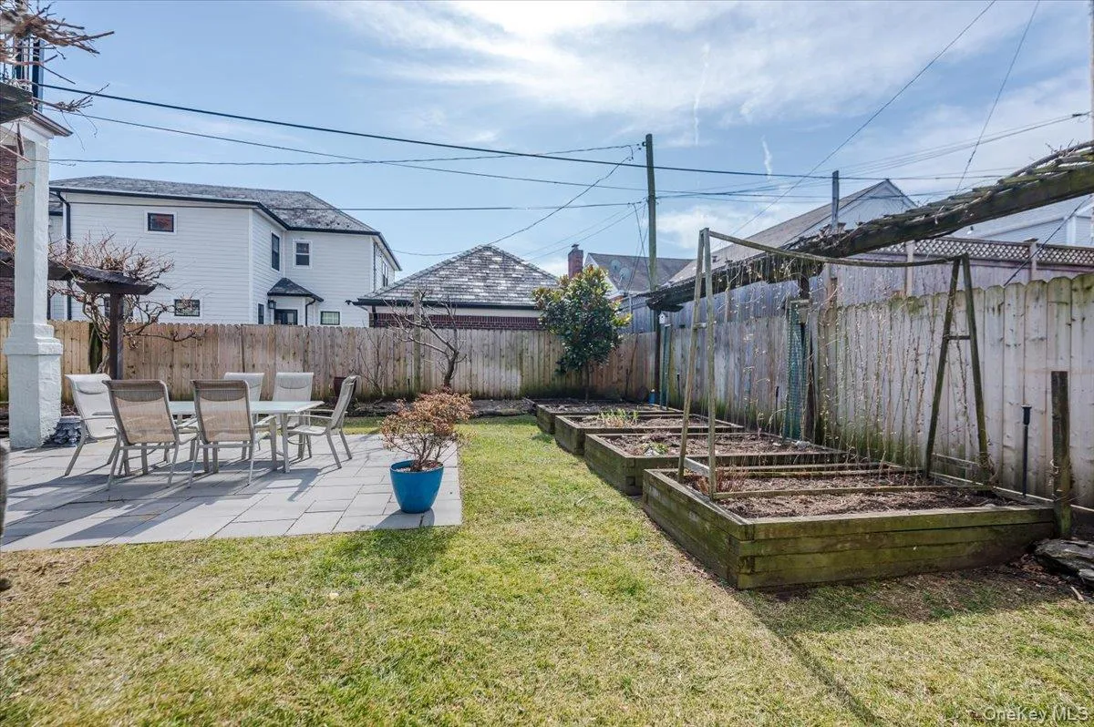View of yard/gardens featuring patios, raised gardening beds, a fenced backyard, and access to lower, garden level/basement View of yard/gardens featuring patios, raised gardening beds, a fenced backyard, and access to lower, garden level/basement
