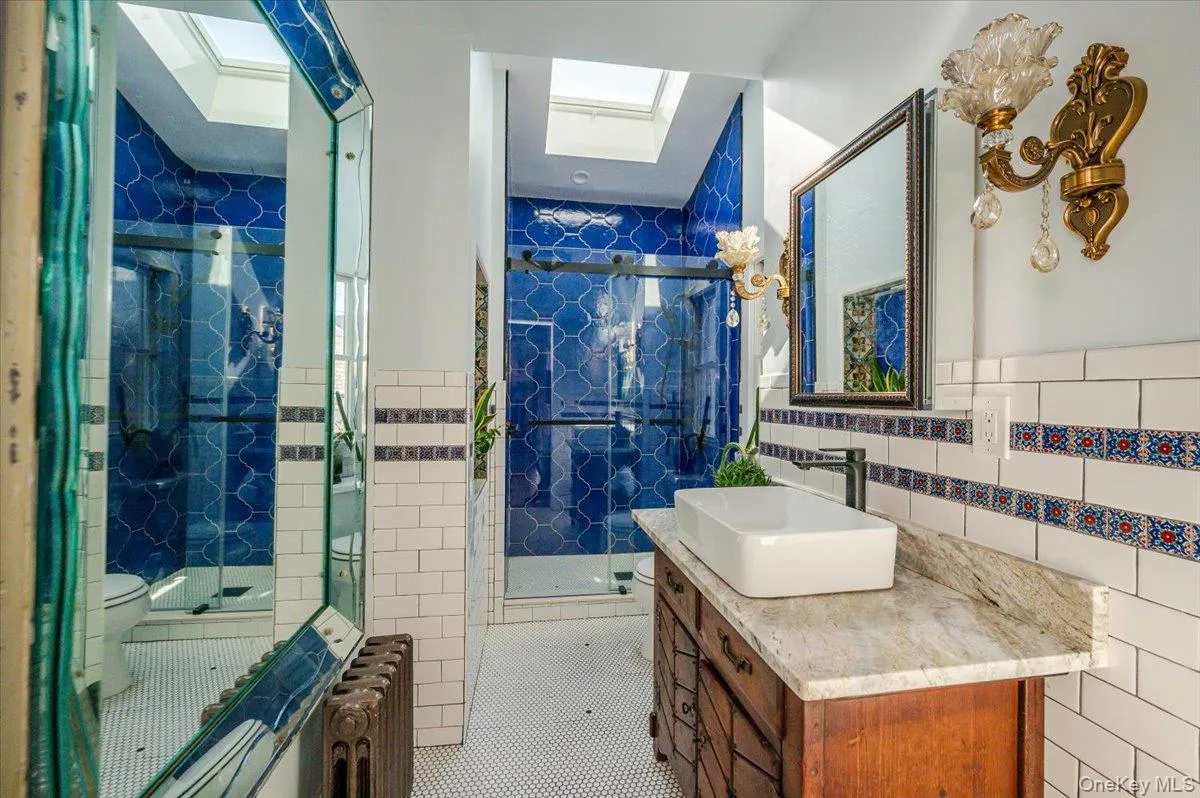 Main Floor Full bathroom with a skylight, a walk in shower, custom tile patterned flooring, and tile walls Main Floor Full bathroom with a skylight, a walk in shower, custom tile patterned flooring, and tile walls