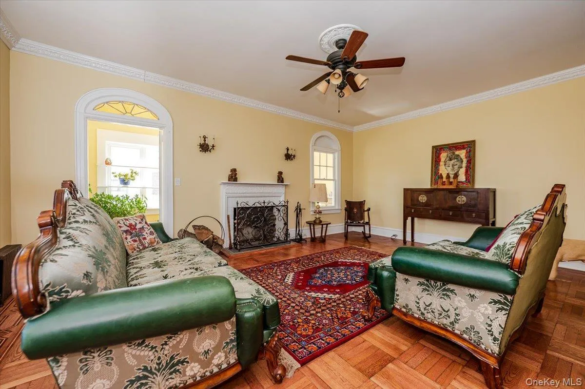 Formal Living area featuring a fireplace, custom redone floors with marquetry inlay, ceiling fan, and beautiful crown molding Formal Living area featuring a fireplace, custom redone floors with marquetry inlay, ceiling fan, and beautiful crown molding