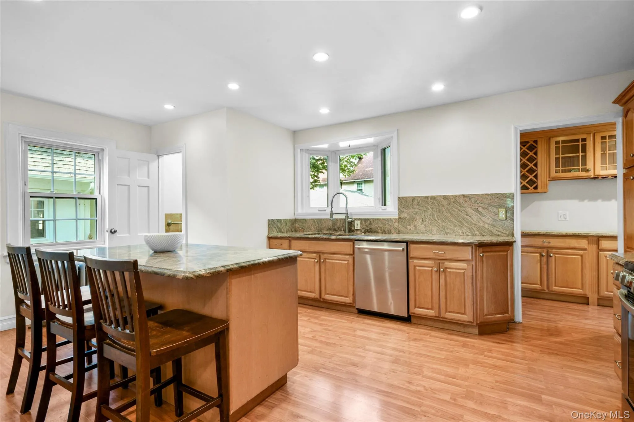 Kitchen featuring recessed lighting, light wood-style flooring, a center island, stainless steel appliances, and decorative backsplash Kitchen featuring recessed lighting, light wood-style flooring, a center island, stainless steel appliances, and decorative backsplash