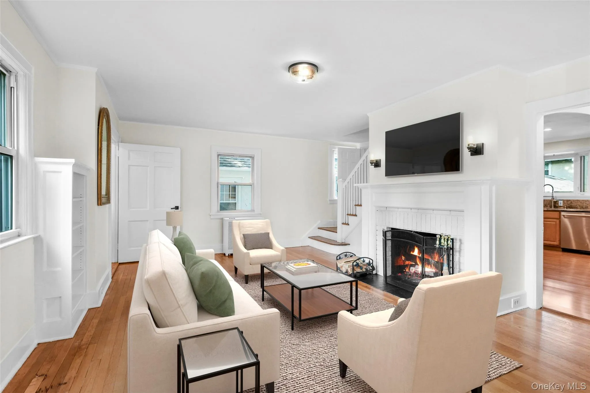 Living room featuring light wood-type flooring, a fireplace, and stairway Living room featuring light wood-type flooring, a fireplace, and stairway