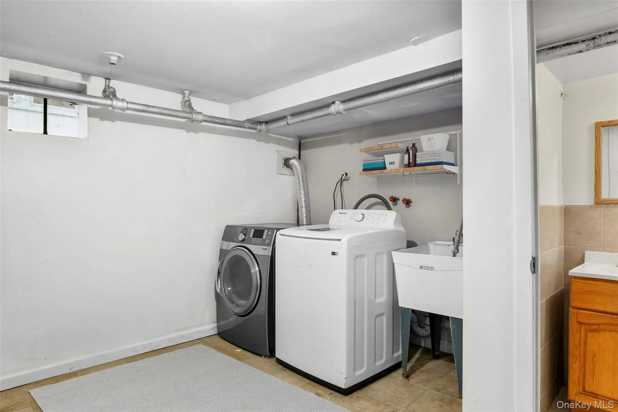 Laundry room with washing machine and clothes dryer, light tile patterned floors, and tile walls Laundry room with washing machine and clothes dryer, light tile patterned floors, and tile walls