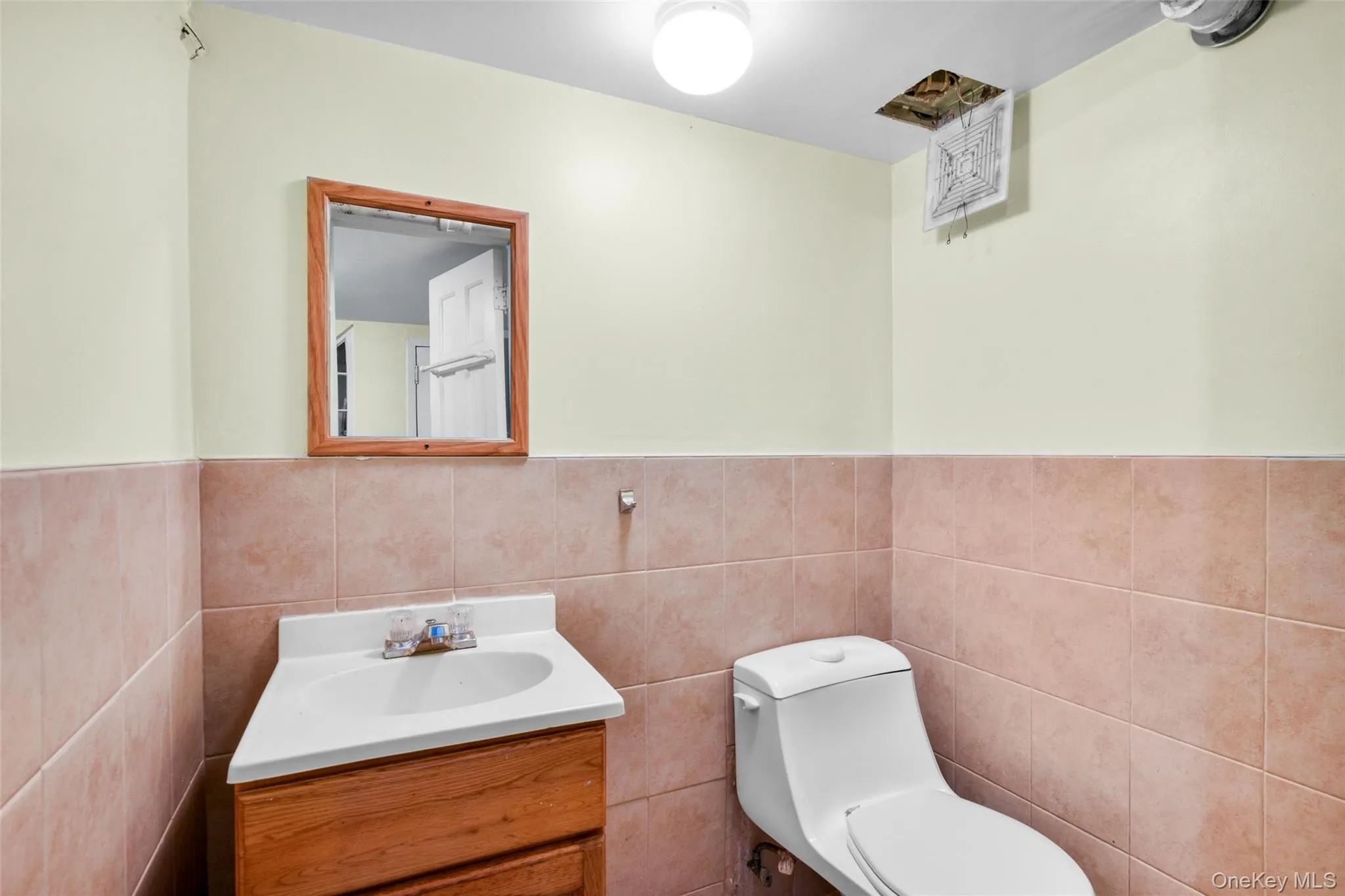 Half bathroom with vanity, tile walls, and a wainscoted wall Half bathroom with vanity, tile walls, and a wainscoted wall