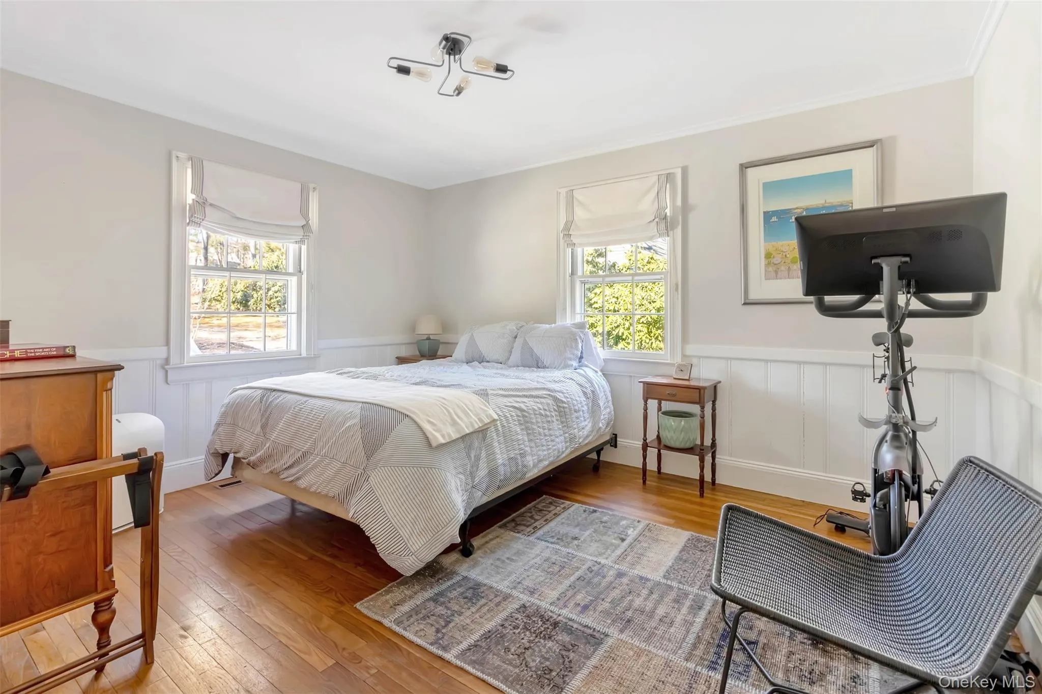 Bedroom featuring a wainscoted wall, multiple windows, and wood-type flooring Bedroom featuring a wainscoted wall, multiple windows, and wood-type flooring