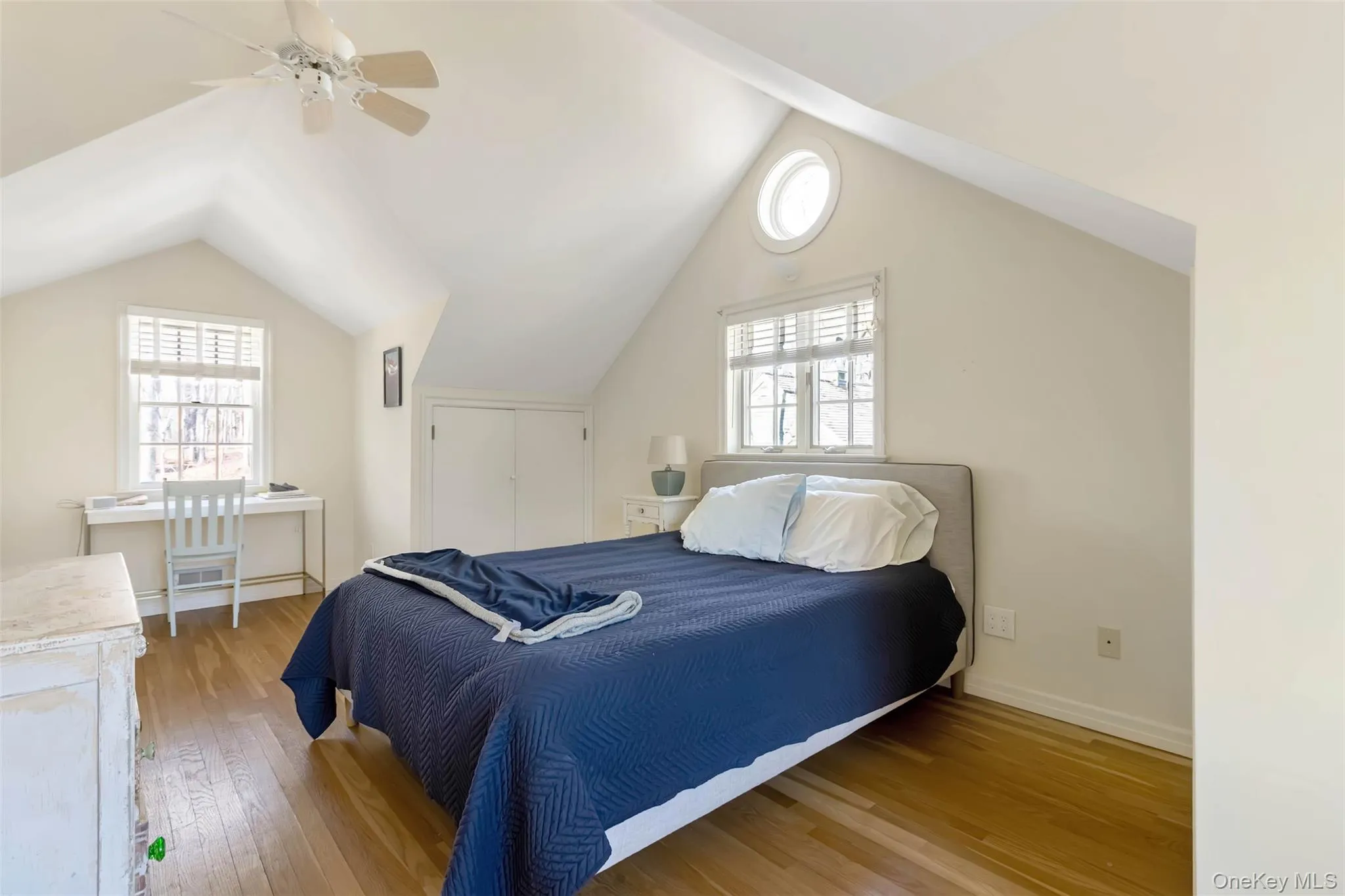 Bedroom with light wood-style floors, ceiling fan, multiple windows, and vaulted ceiling Bedroom with light wood-style floors, ceiling fan, multiple windows, and vaulted ceiling