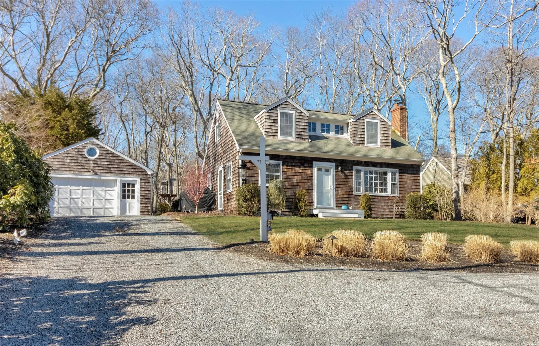 View of front facade featuring an outbuilding, gravel driveway, a detached garage, a chimney, and a front lawn View of front facade featuring an outbuilding, gravel driveway, a detached garage, a chimney, and a front lawn