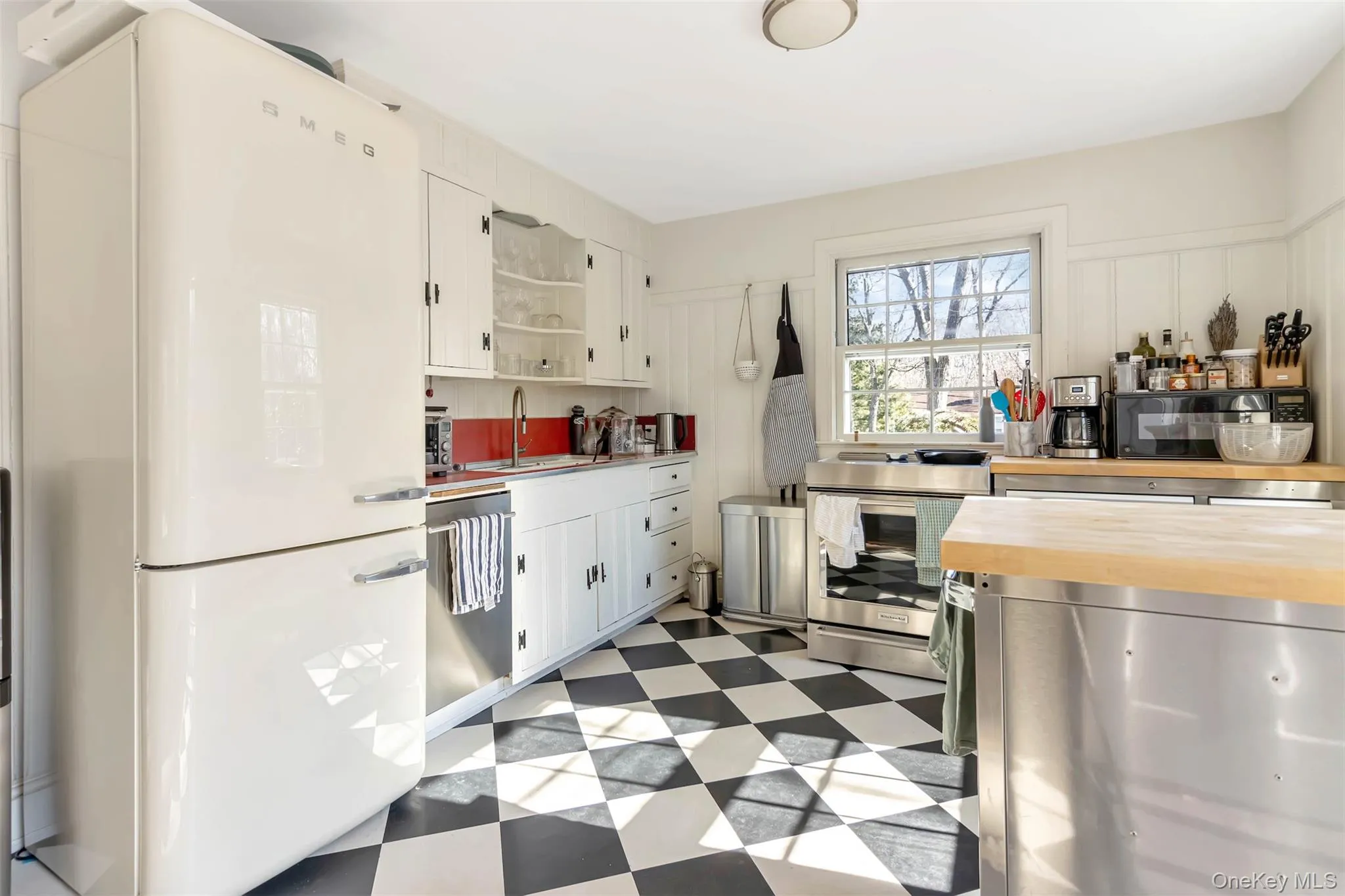 Kitchen with a sink, wood counters, white cabinetry, appliances with stainless steel finishes, and light floors Kitchen with a sink, wood counters, white cabinetry, appliances with stainless steel finishes, and light floors