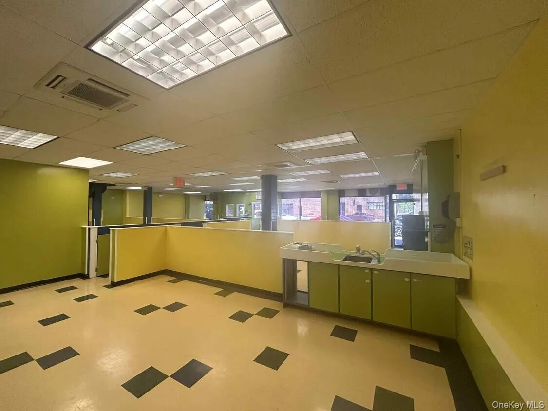 Kitchen with light countertops, light flooring, green cabinetry, and a paneled ceiling Kitchen with light countertops, light flooring, green cabinetry, and a paneled ceiling