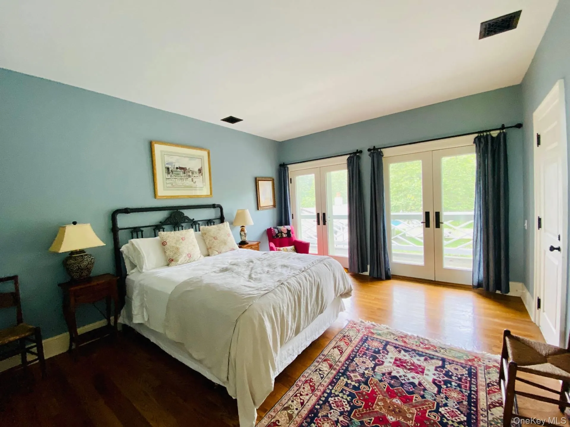 Bedroom featuring wood finished floors, visible vents, baseboards, access to outside, and french doors Bedroom featuring wood finished floors, visible vents, baseboards, access to outside, and french doors