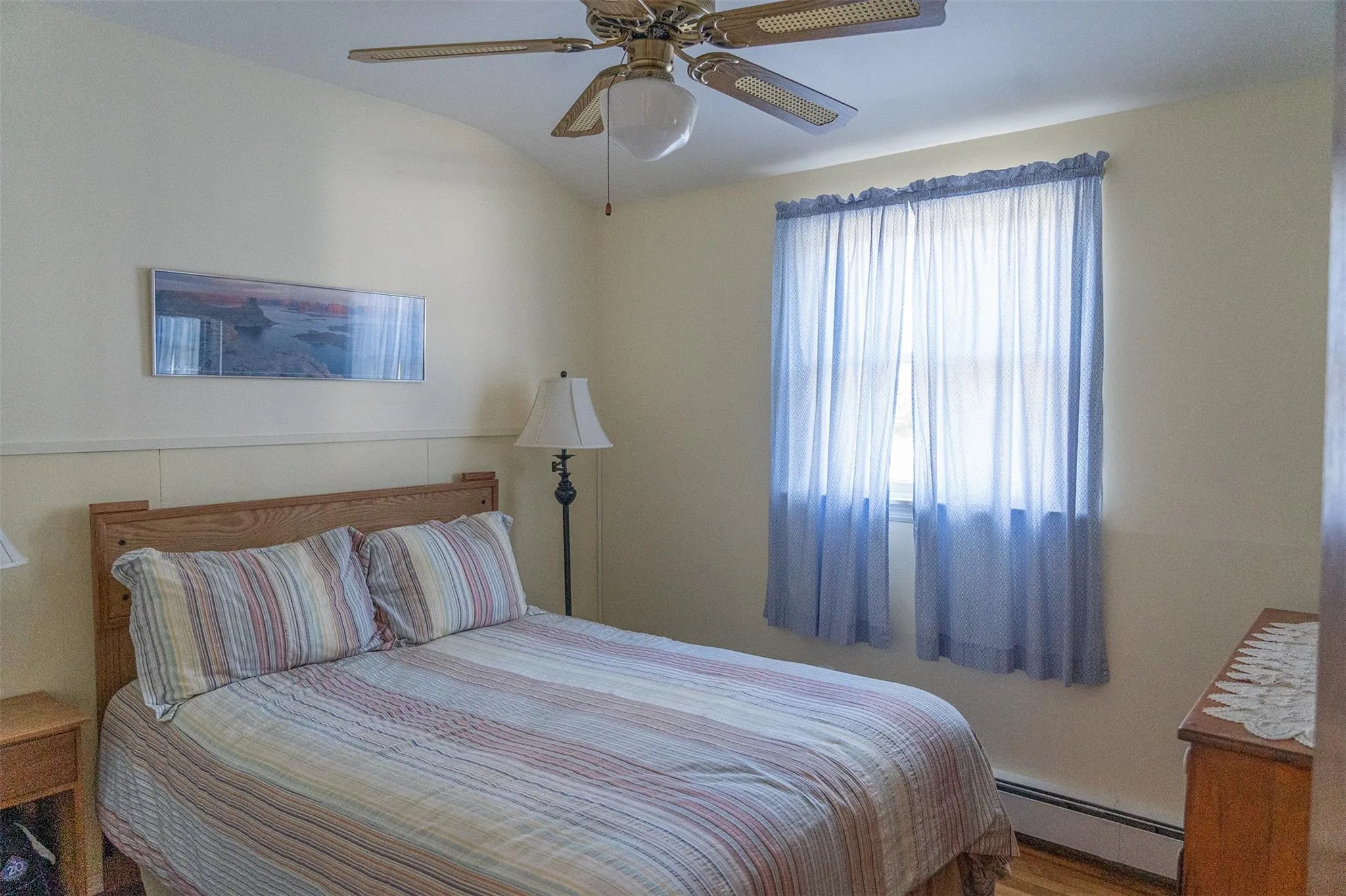 Bedroom with a baseboard heating unit, lofted ceiling, and ceiling fan Bedroom with a baseboard heating unit, lofted ceiling, and ceiling fan