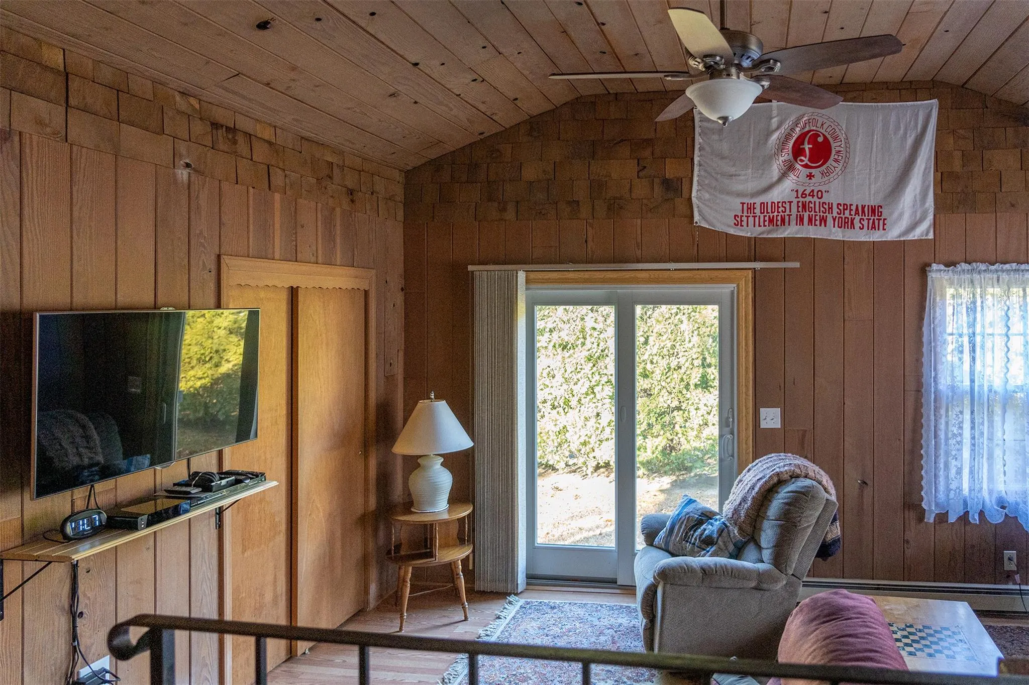 Living room with lofted ceiling, wooden walls, plenty of natural light, and wood ceiling Living room with lofted ceiling, wooden walls, plenty of natural light, and wood ceiling