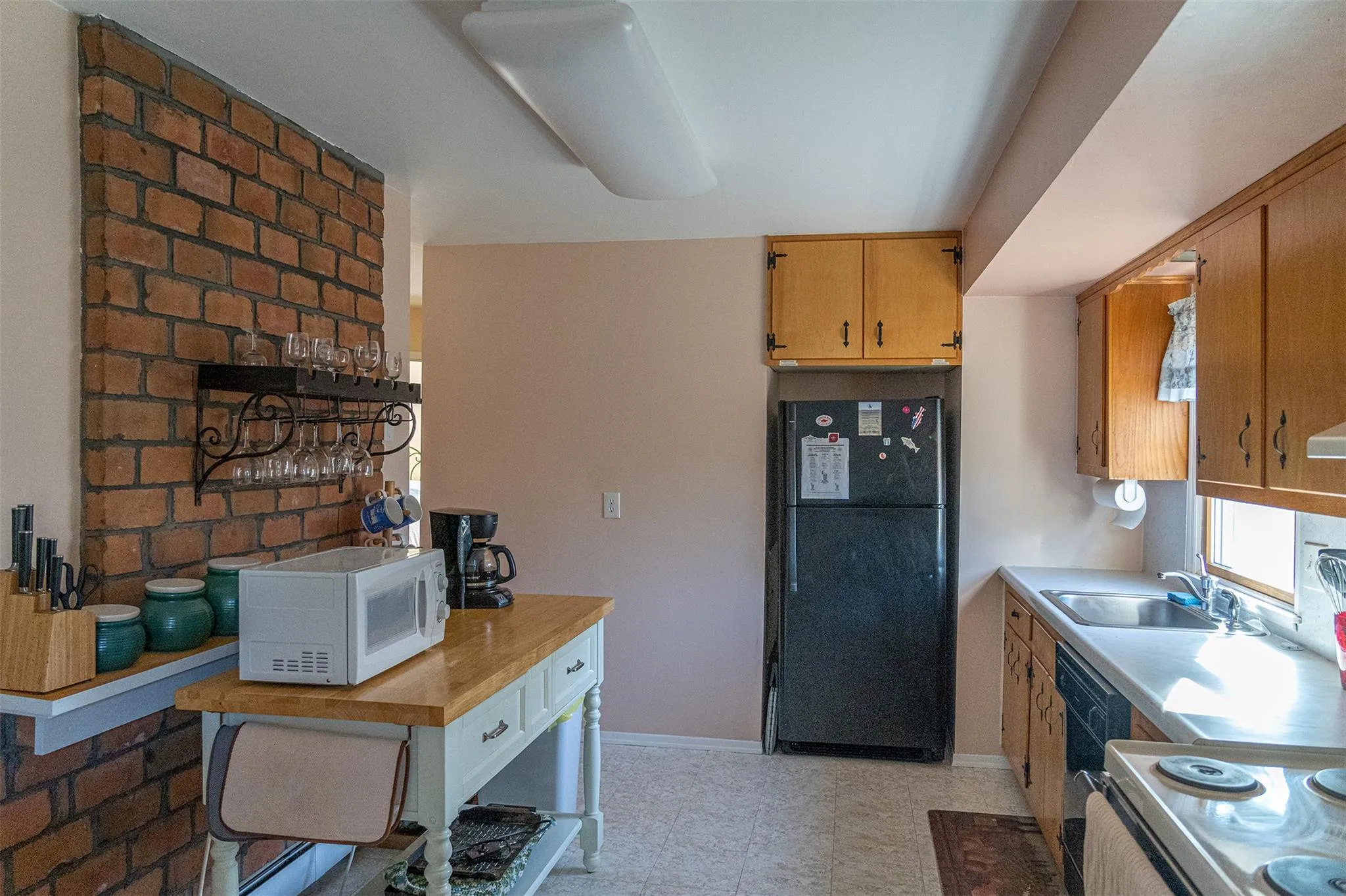 Kitchen with black appliances, baseboards, light countertops, and a sink Kitchen with black appliances, baseboards, light countertops, and a sink