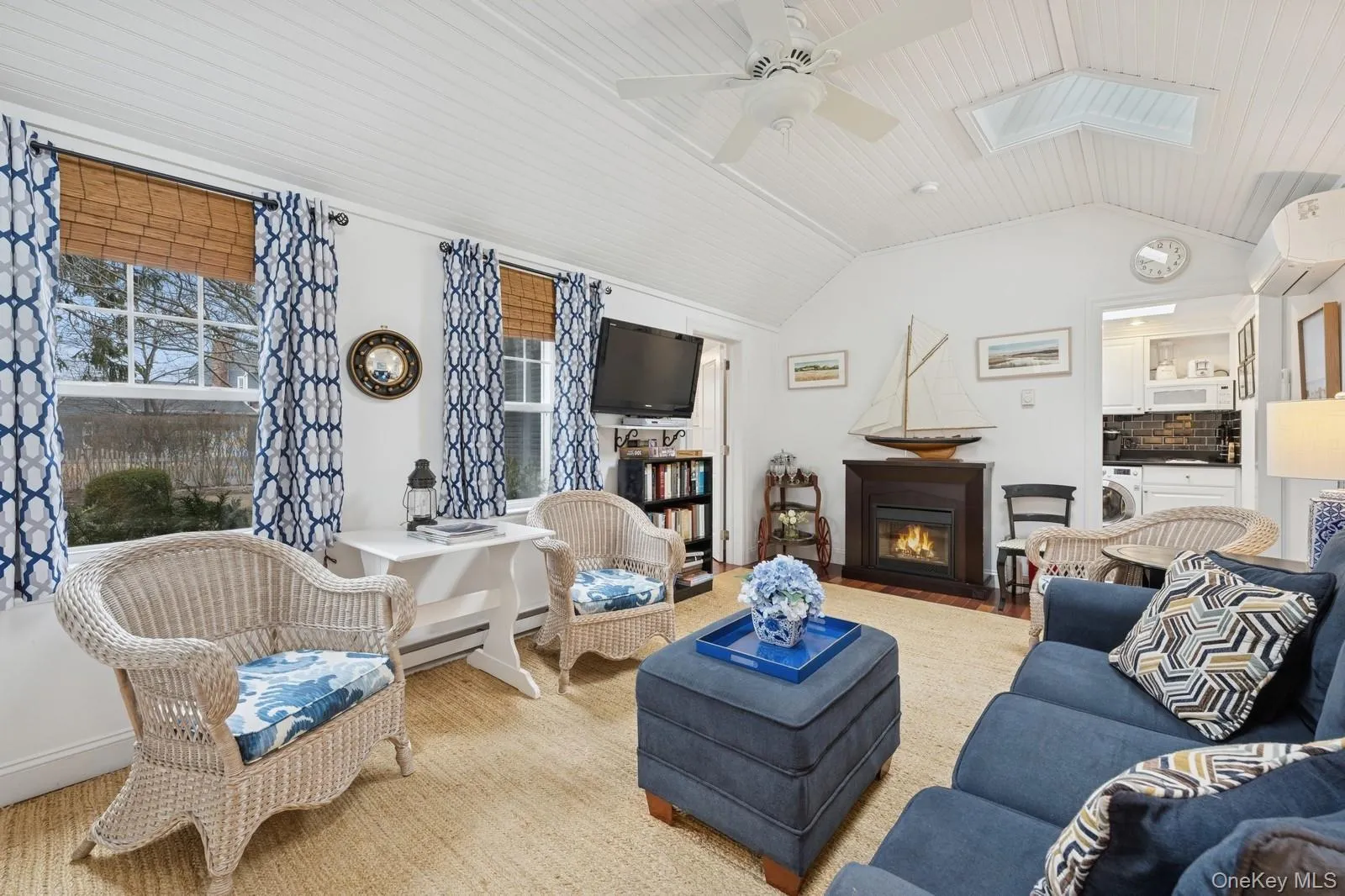 Living area with washer / dryer, lofted ceiling with skylight, a fireplace with flush hearth, ceiling fan, and a wall mounted AC Living area with washer / dryer, lofted ceiling with skylight, a fireplace with flush hearth, ceiling fan, and a wall mounted AC
