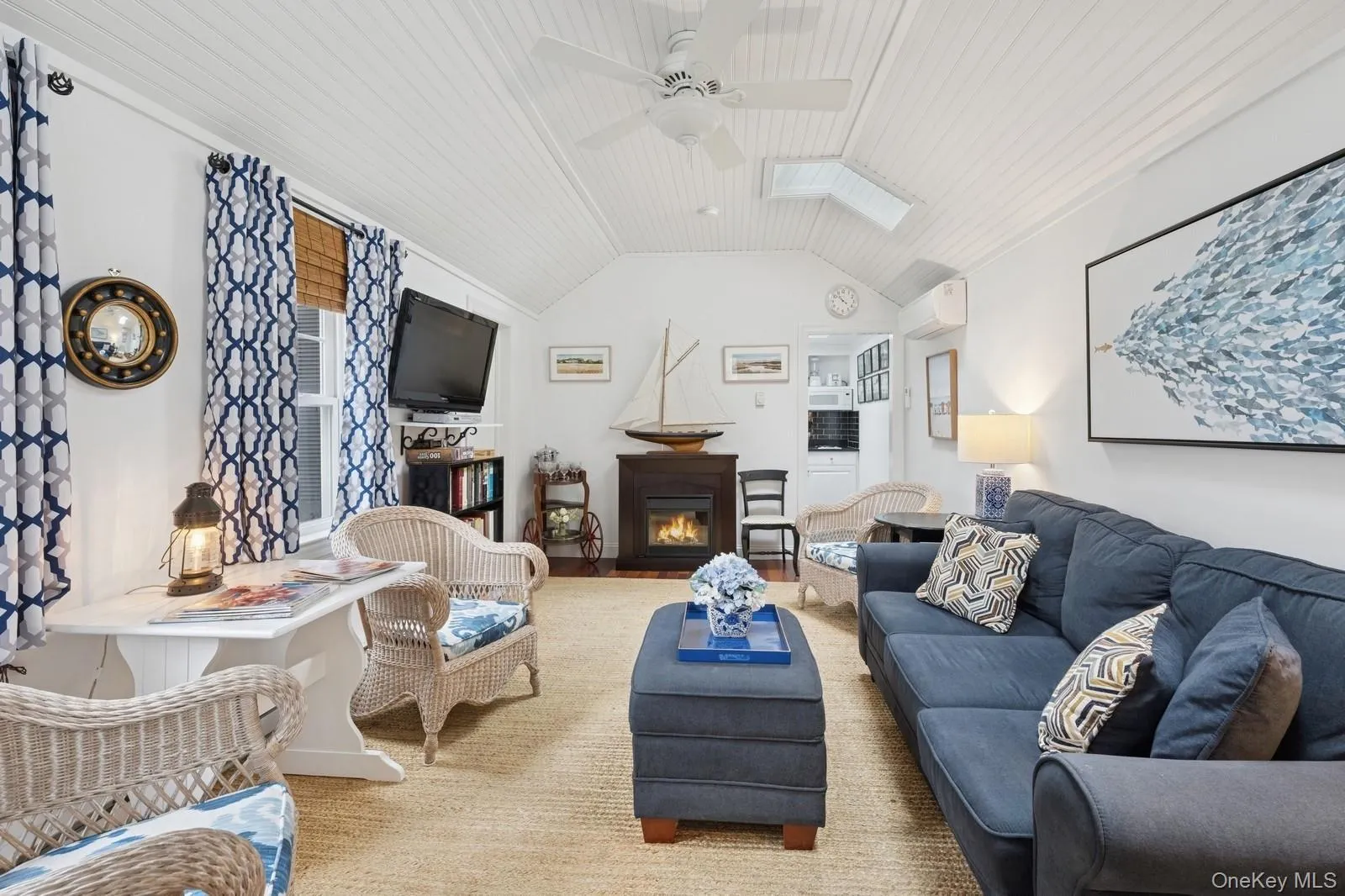 Living room with lofted ceiling with skylight, a glass covered fireplace, an AC wall unit, ceiling fan, and wooden ceiling Living room with lofted ceiling with skylight, a glass covered fireplace, an AC wall unit, ceiling fan, and wooden ceiling