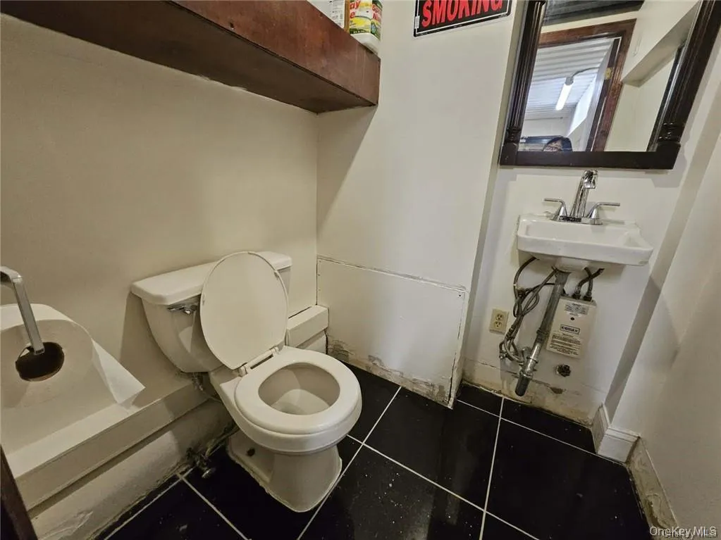 Half bath with toilet, tile patterned flooring, and a sink Half bath with toilet, tile patterned flooring, and a sink