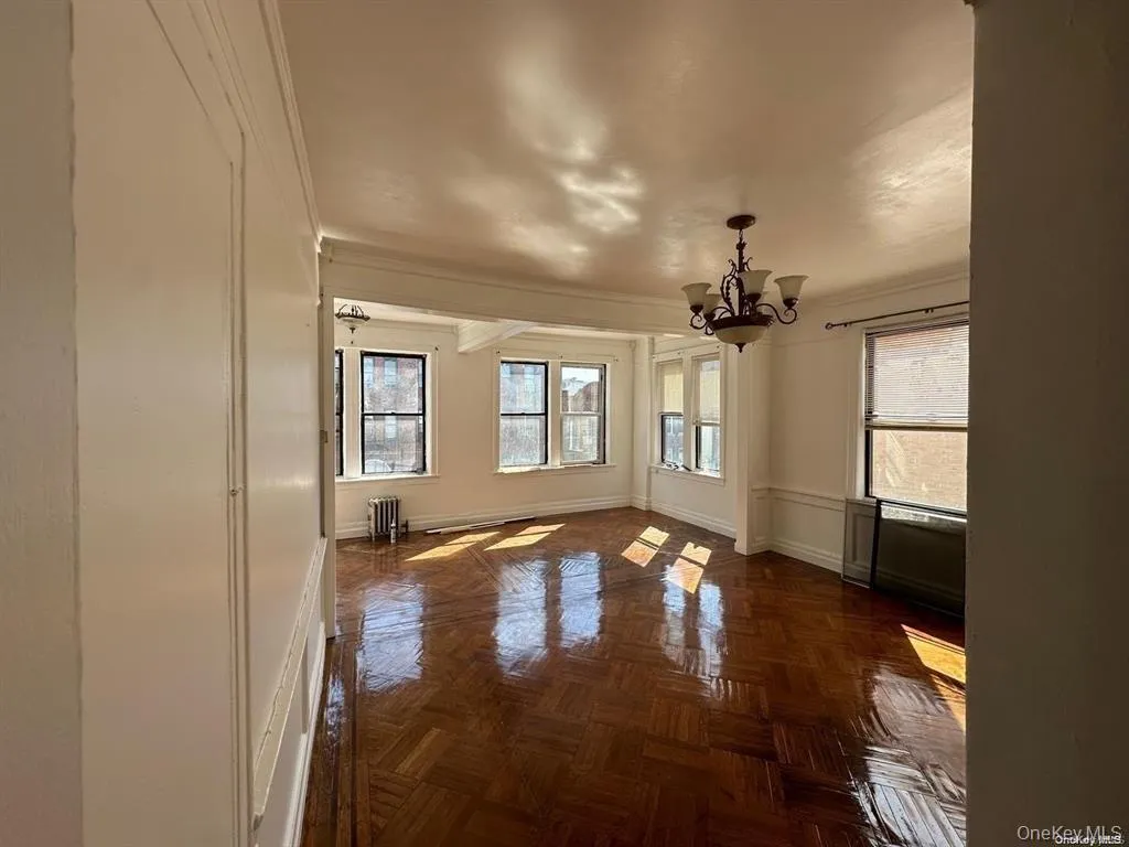 Unfurnished room featuring a chandelier, crown molding, and radiator heating unit Unfurnished room featuring a chandelier, crown molding, and radiator heating unit