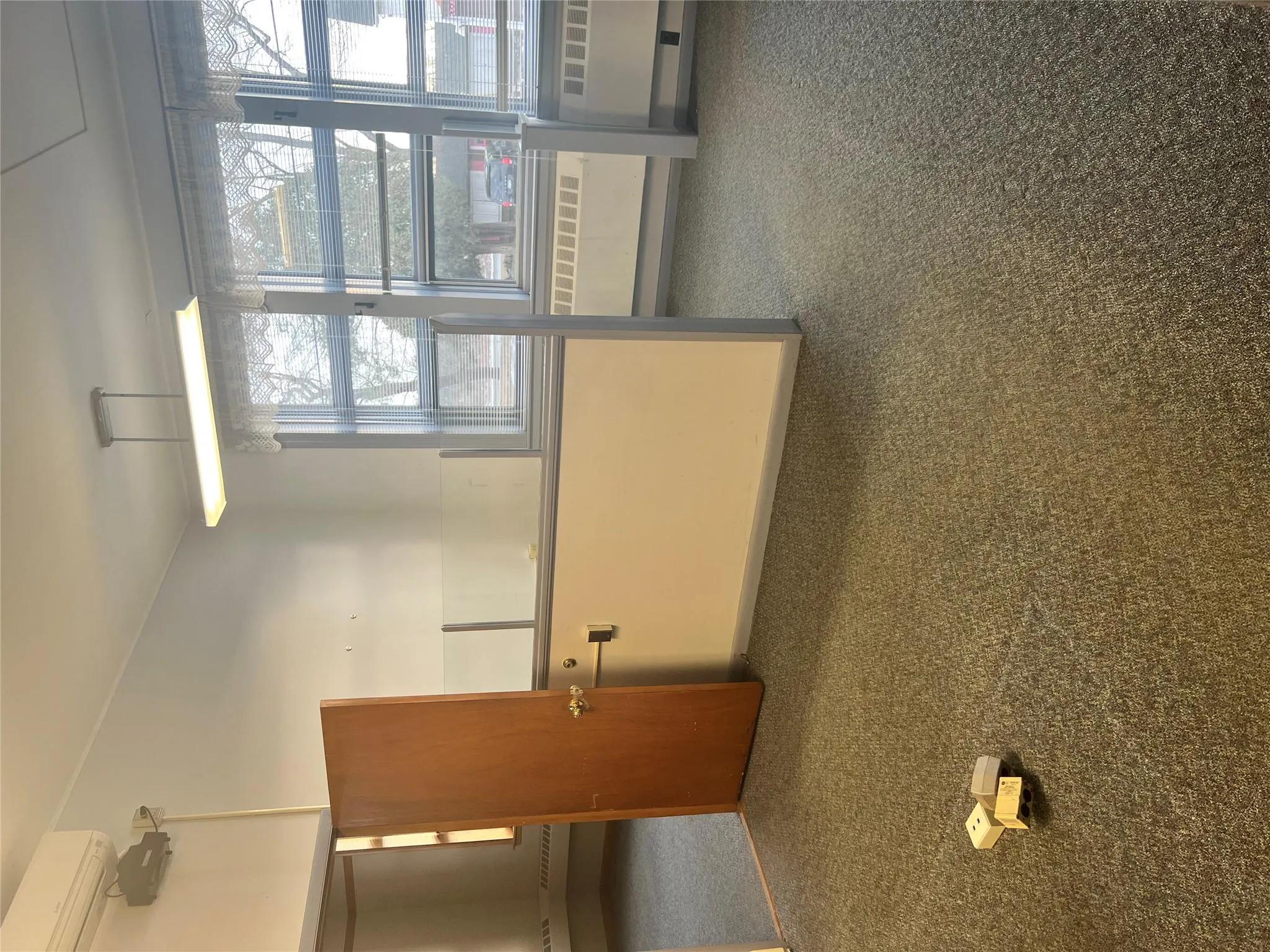 Carpeted empty room featuring a wall mounted AC and a wealth of natural light Carpeted empty room featuring a wall mounted AC and a wealth of natural light