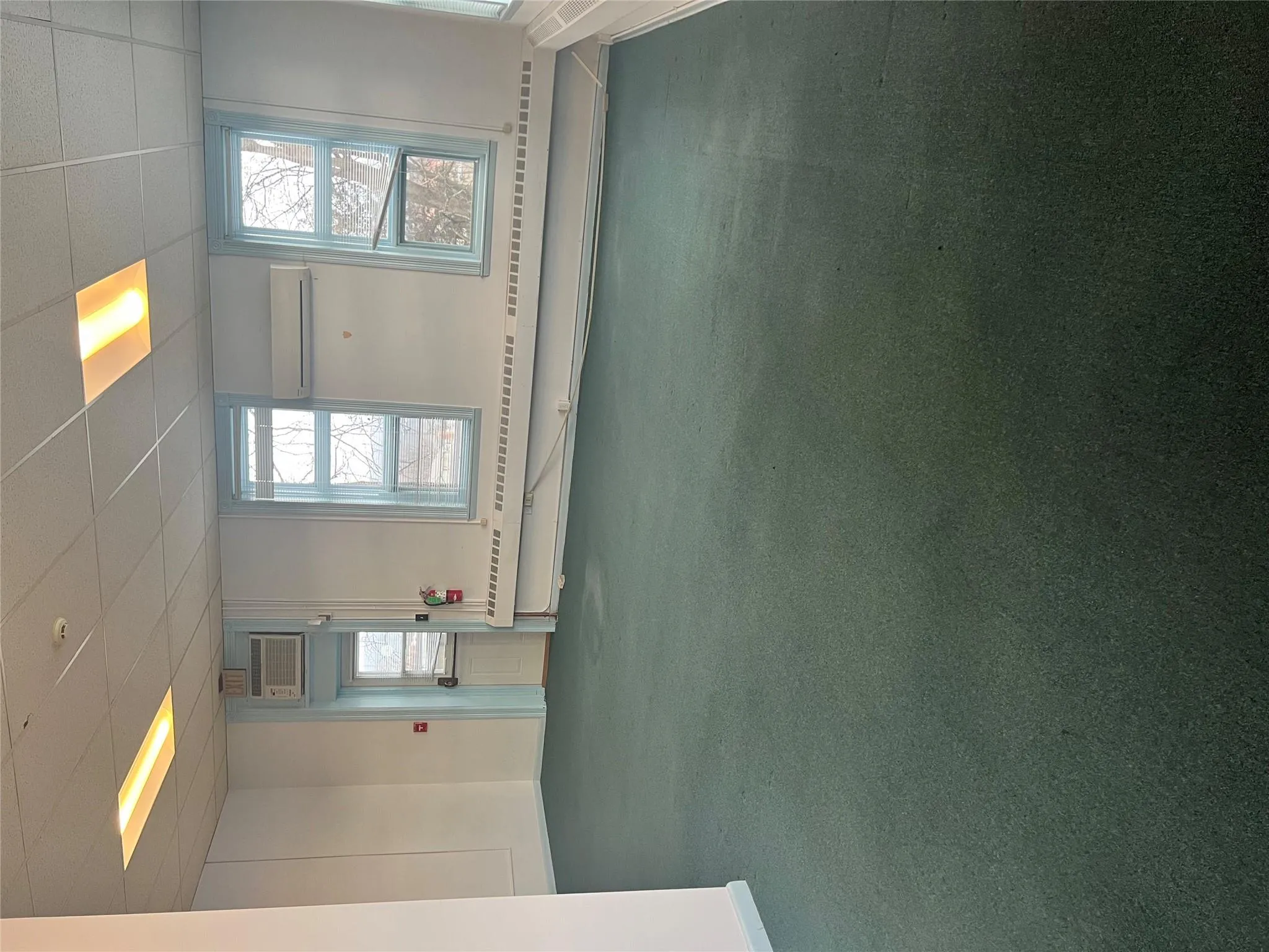 Spare room featuring a drop ceiling, a wall unit AC, carpet floors, baseboards, and an AC wall unit Spare room featuring a drop ceiling, a wall unit AC, carpet floors, baseboards, and an AC wall unit