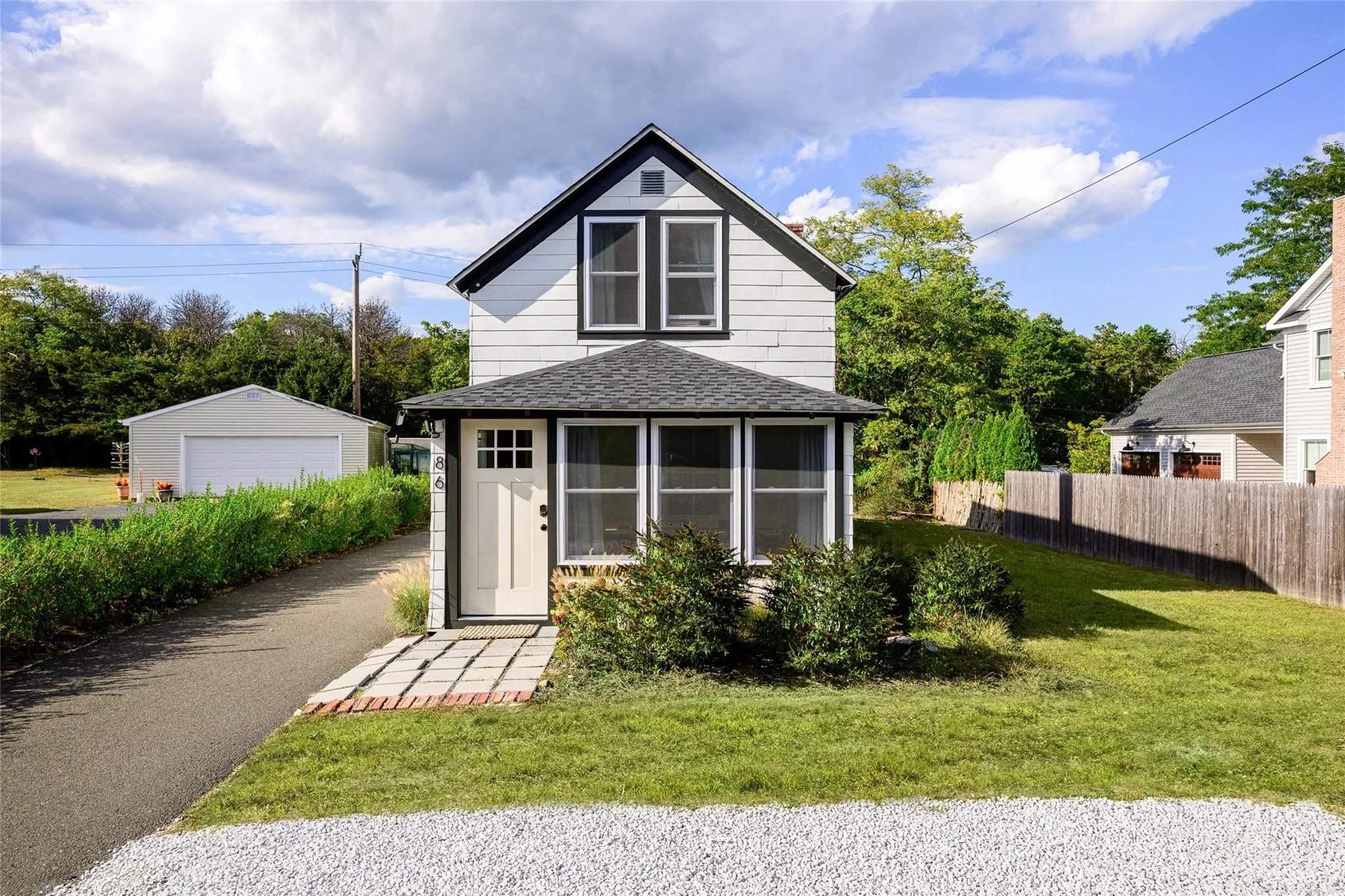 View of front of property with a detached garage, an outbuilding, roof with shingles, fence, and a front lawn View of front of property with a detached garage, an outbuilding, roof with shingles, fence, and a front lawn
