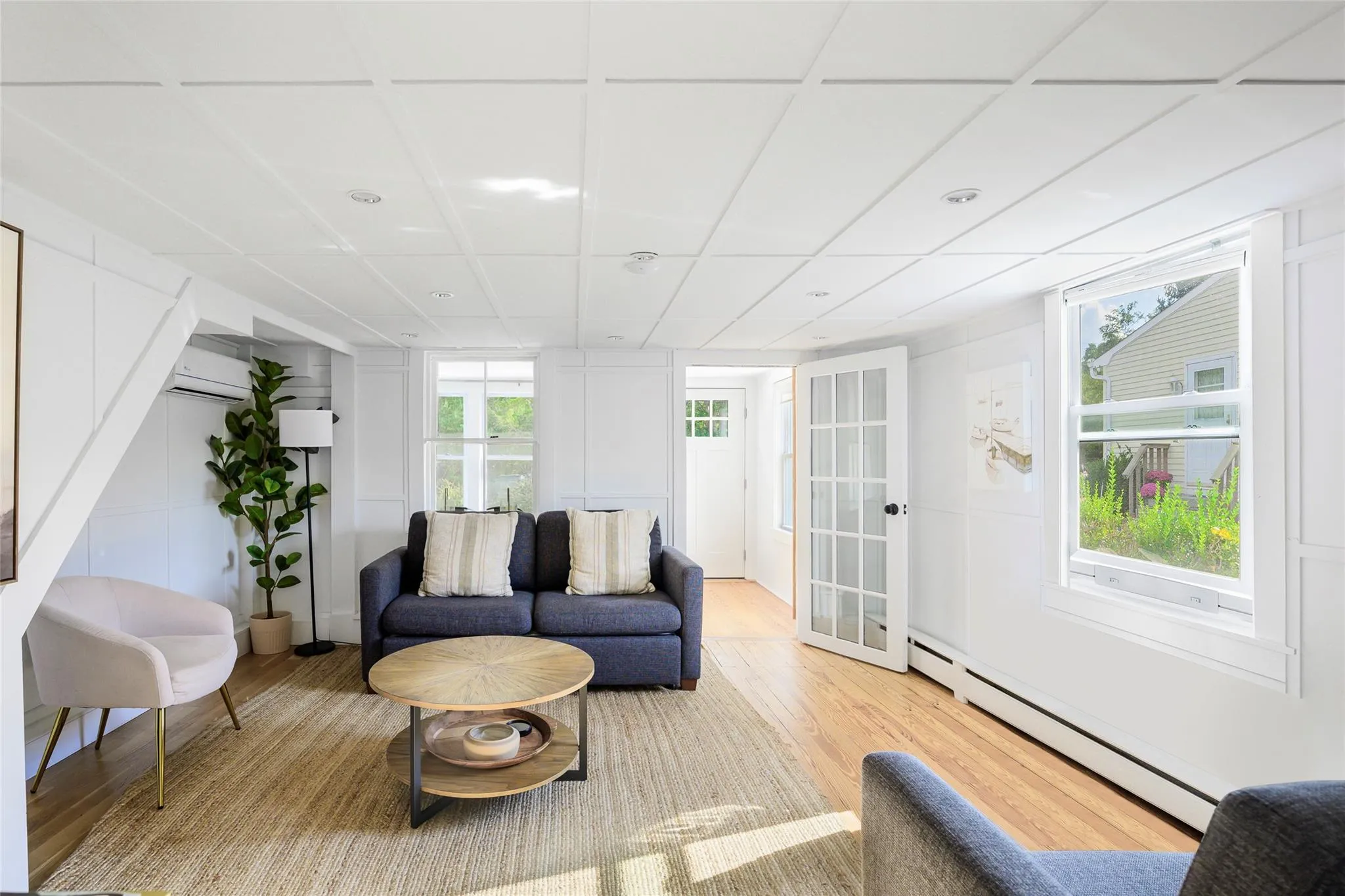 Living area decorative wall, a baseboard radiator, a paneled ceiling, and light wood-style floors Living area decorative wall, a baseboard radiator, a paneled ceiling, and light wood-style floors
