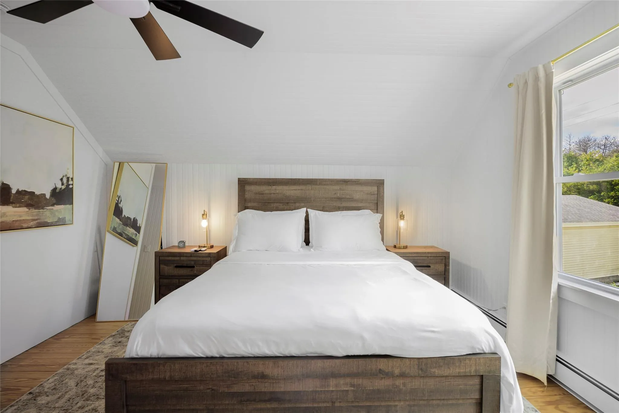Bedroom with ceiling fan, a baseboard radiator, vaulted ceiling, and wood finished floors Bedroom with ceiling fan, a baseboard radiator, vaulted ceiling, and wood finished floors