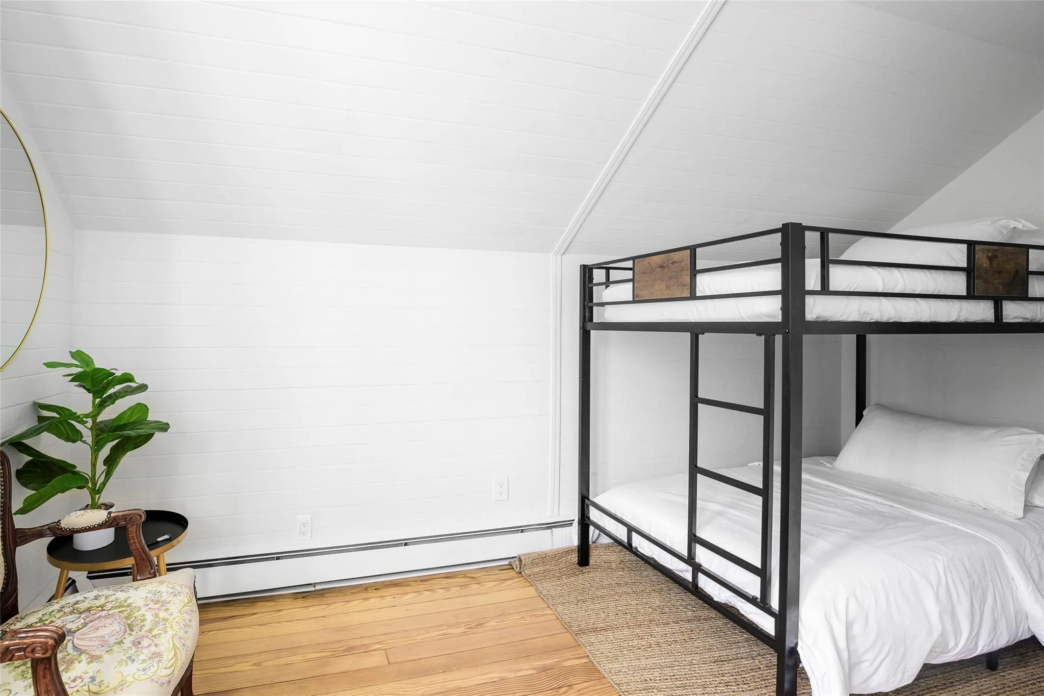 Bedroom featuring a baseboard heating unit, vaulted ceiling, and wood finished floors Bedroom featuring a baseboard heating unit, vaulted ceiling, and wood finished floors