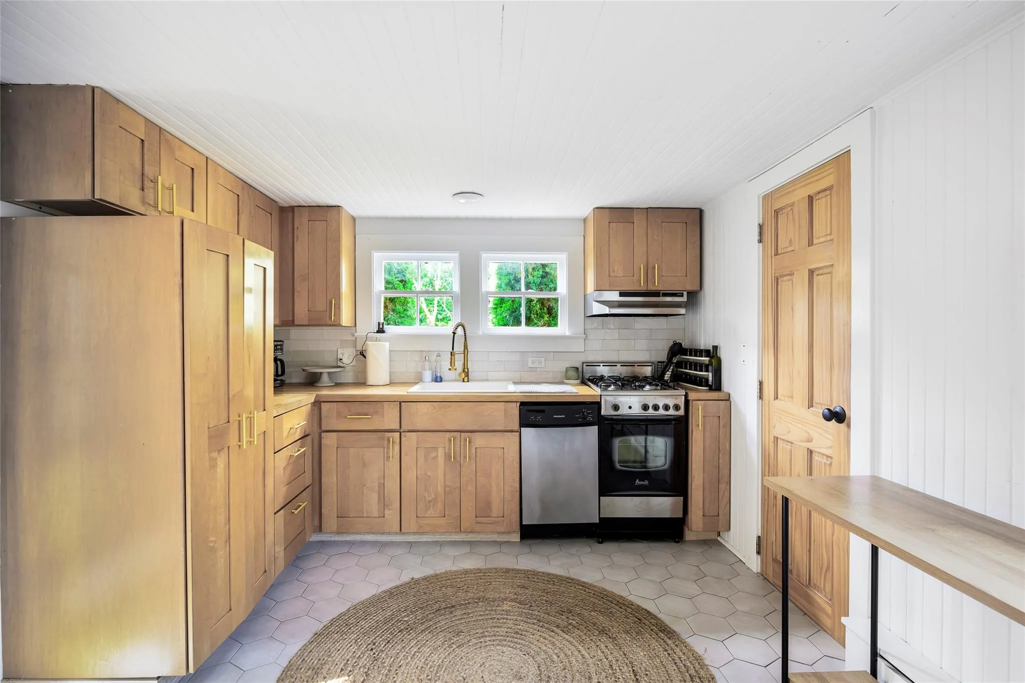 Kitchen with under cabinet range hood, a sink, stainless steel dishwasher, decorative backsplash, and gas range oven Kitchen with under cabinet range hood, a sink, stainless steel dishwasher, decorative backsplash, and gas range oven