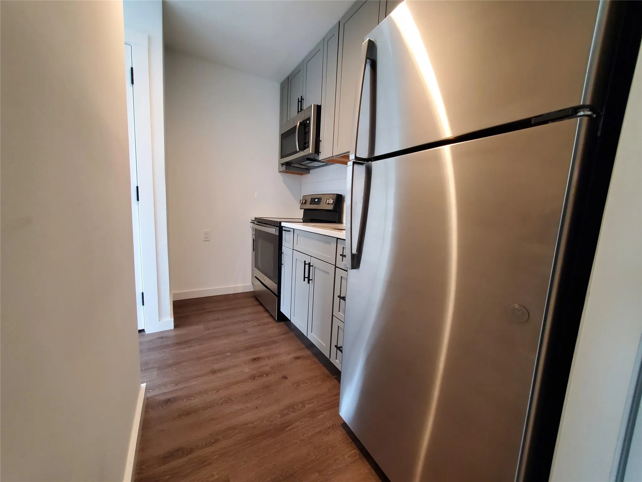 Kitchen featuring gray cabinets, light countertops, stainless steel appliances, and baseboards Kitchen featuring gray cabinets, light countertops, stainless steel appliances, and baseboards