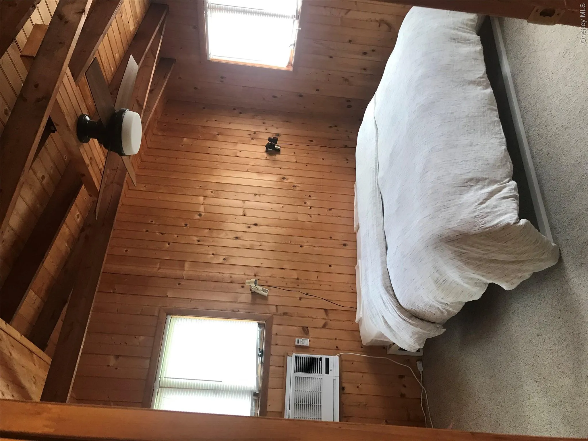 Carpeted bedroom featuring wood walls, beamed ceiling, wooden ceiling, and cooling unit Carpeted bedroom featuring wood walls, beamed ceiling, wooden ceiling, and cooling unit