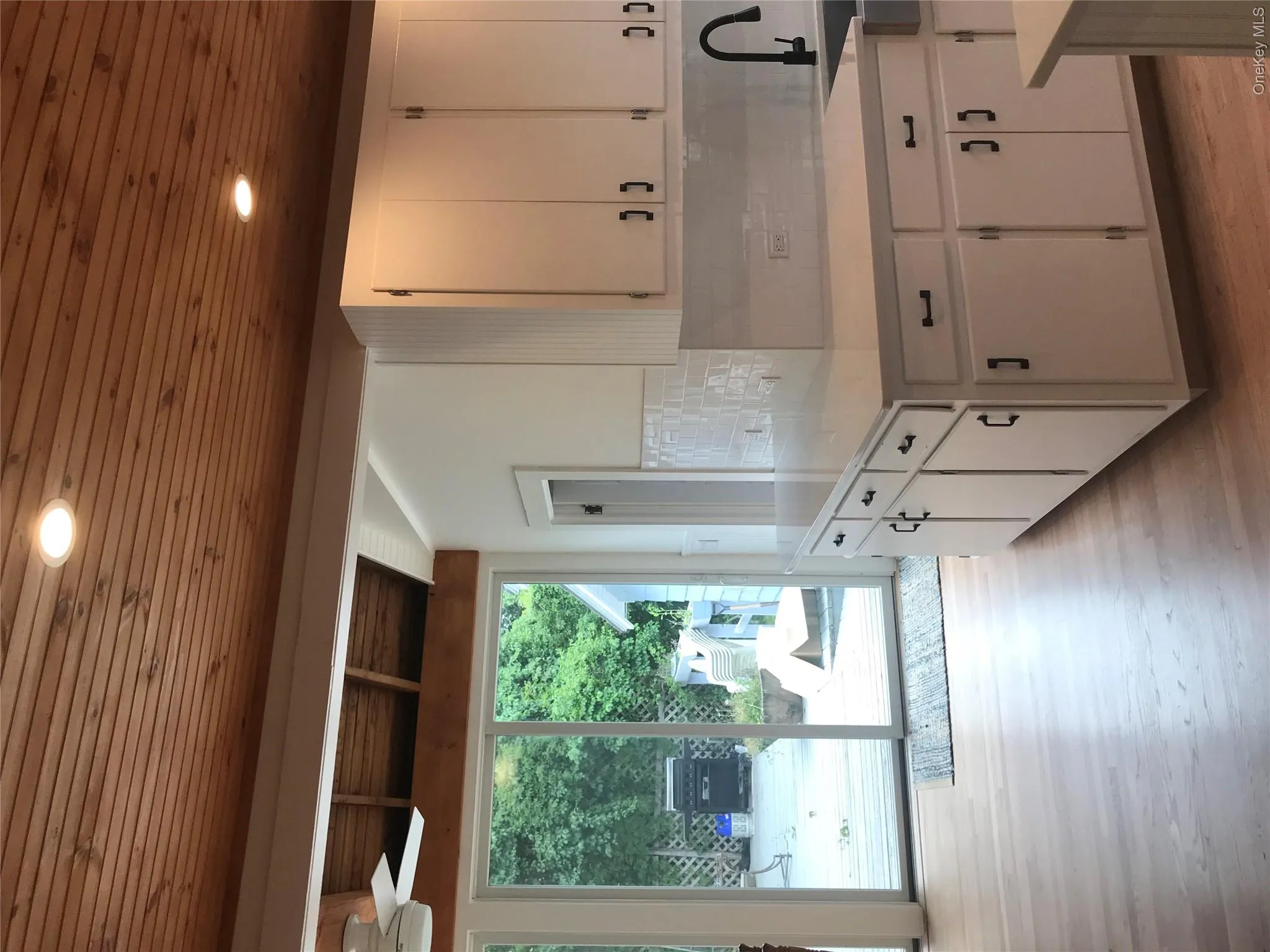 Kitchen with white cabinets, wooden ceiling, light countertops, light wood-type flooring, and backsplash Kitchen with white cabinets, wooden ceiling, light countertops, light wood-type flooring, and backsplash