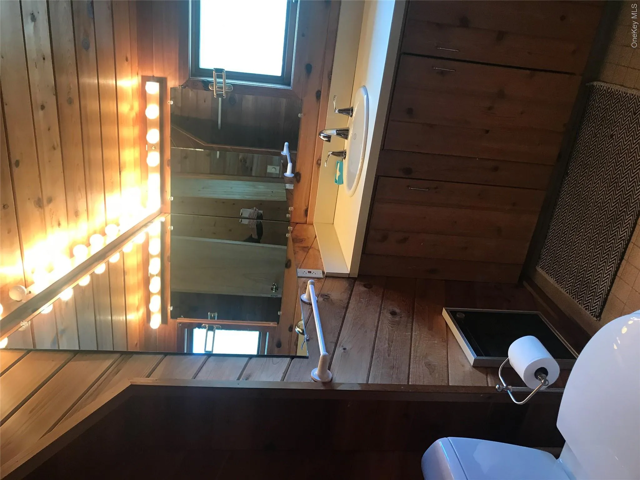 Bathroom featuring wooden walls, toilet, and a healthy amount of sunlight Bathroom featuring wooden walls, toilet, and a healthy amount of sunlight