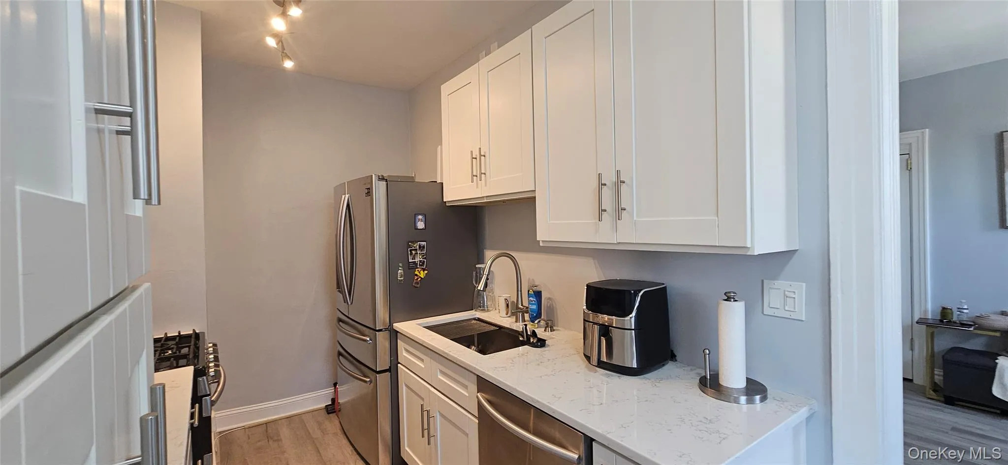 Kitchen featuring light stone counters, a sink, baseboards, white cabinets, and light wood finished floors Kitchen featuring light stone counters, a sink, baseboards, white cabinets, and light wood finished floors