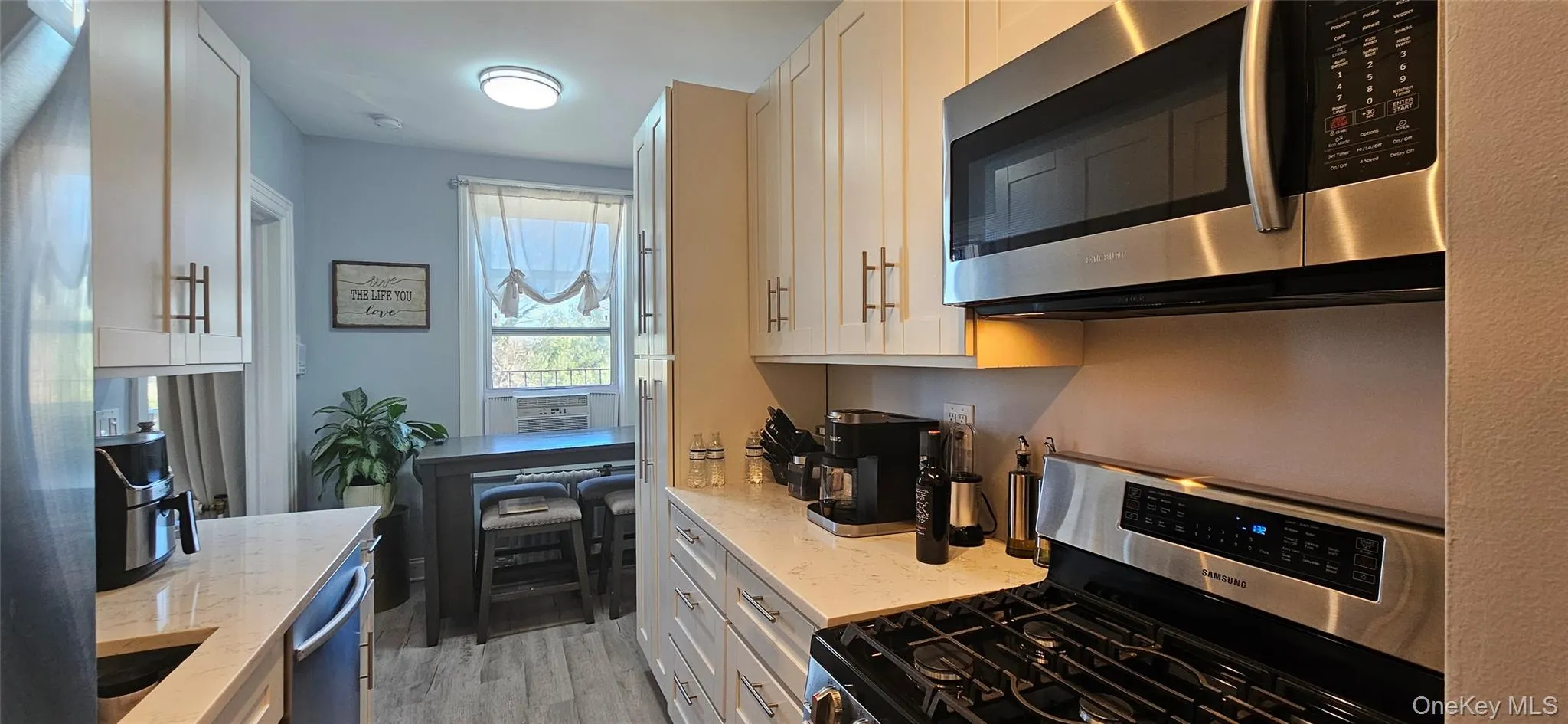 Kitchen with white cabinets, light stone countertops, stainless steel appliances, and light wood finished floors Kitchen with white cabinets, light stone countertops, stainless steel appliances, and light wood finished floors