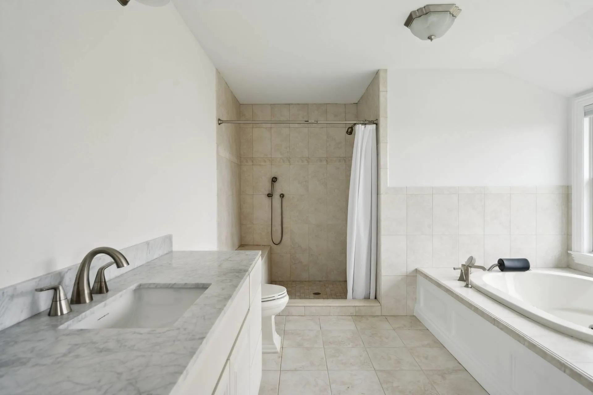 Spacious Primary Bath featuring lofted ceiling, a garden tub, toilet, tile patterned floors, and a stall shower Spacious Primary Bath featuring lofted ceiling, a garden tub, toilet, tile patterned floors, and a stall shower