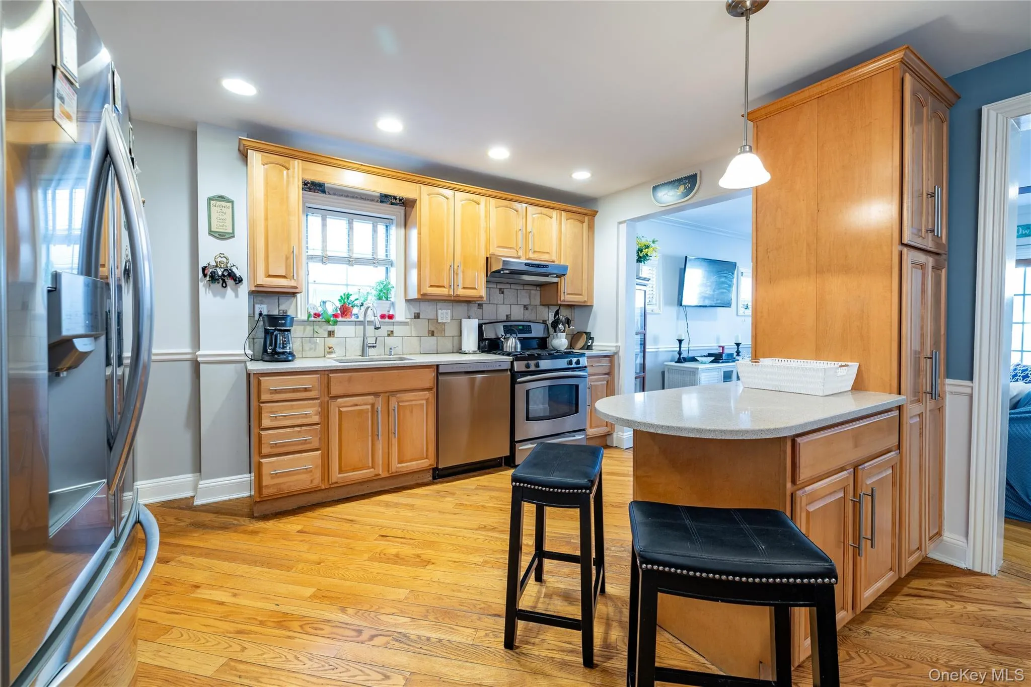 Kitchen with stainless steel appliances, a sink, light wood-style flooring, and under cabinet range hood Kitchen with stainless steel appliances, a sink, light wood-style flooring, and under cabinet range hood