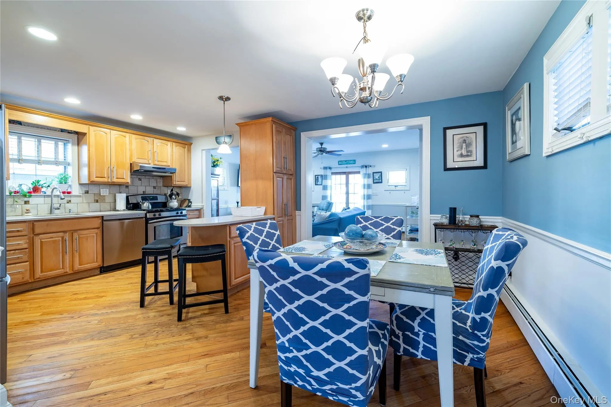 Dining room featuring ceiling fan with notable chandelier, a baseboard radiator, light wood-style flooring, and recessed lighting Dining room featuring ceiling fan with notable chandelier, a baseboard radiator, light wood-style flooring, and recessed lighting