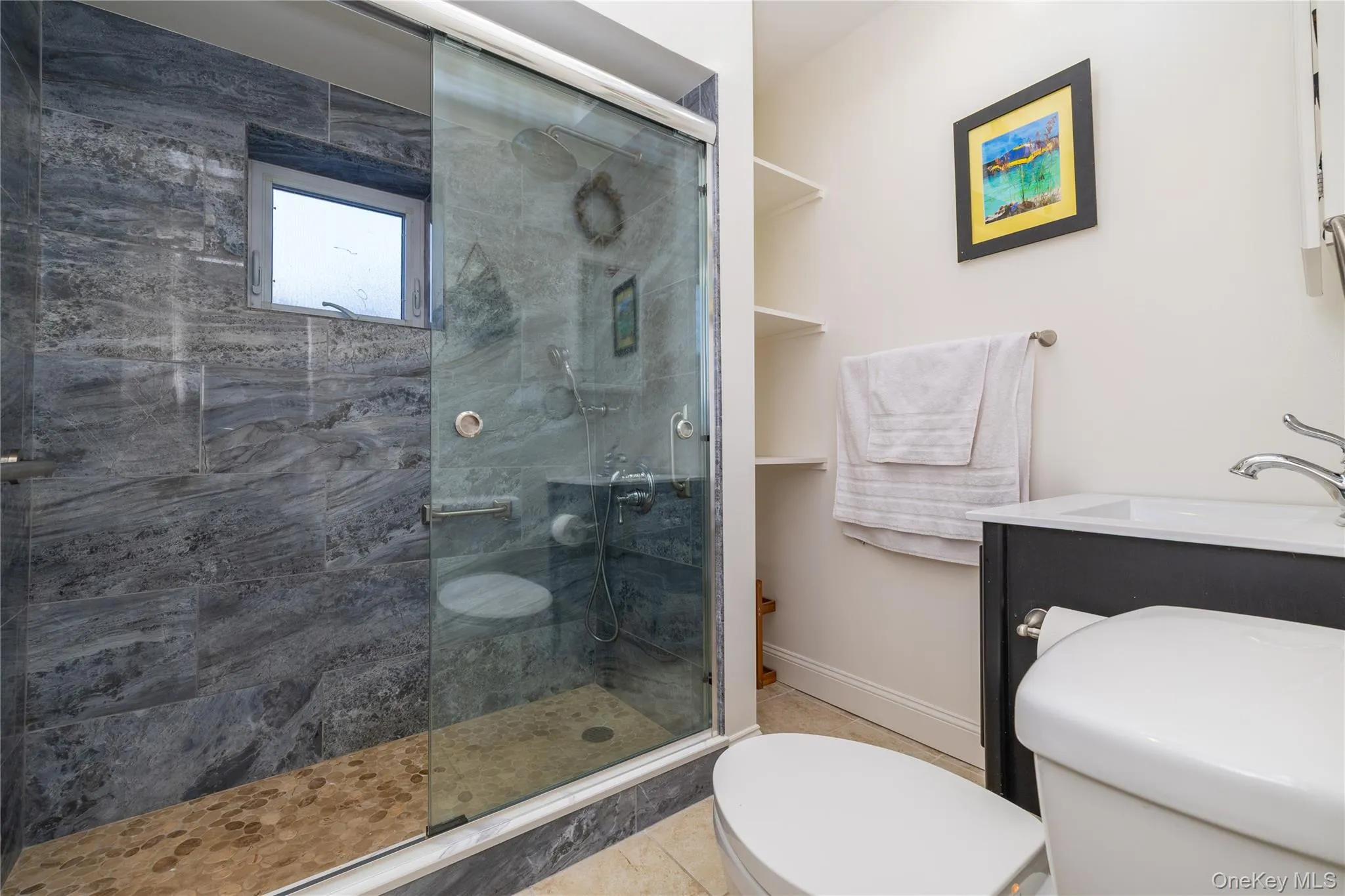 Bathroom featuring toilet, a stall shower, a sink, baseboards, and tile patterned floors Bathroom featuring toilet, a stall shower, a sink, baseboards, and tile patterned floors