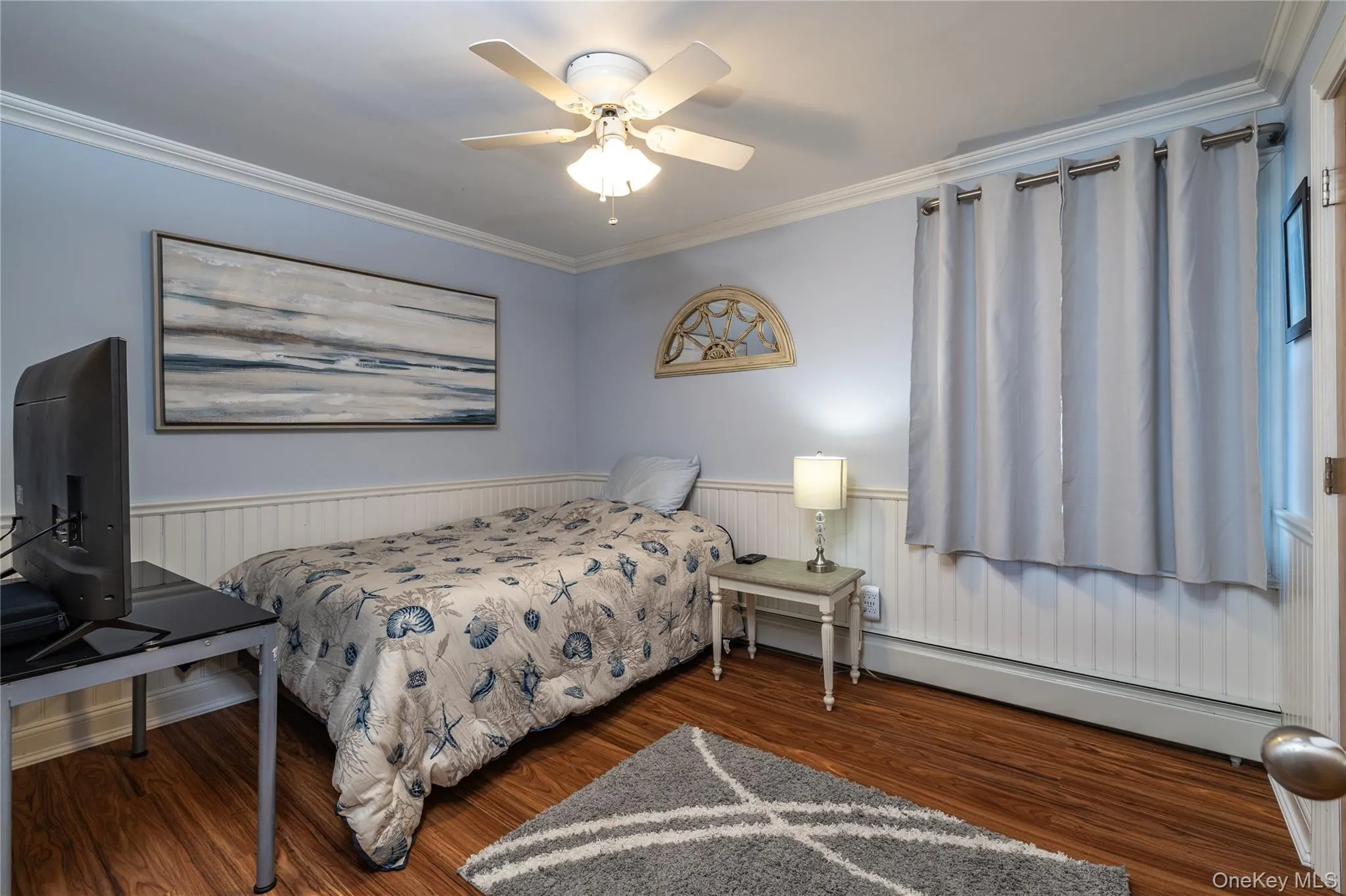 Bedroom featuring a ceiling fan, wainscoting, crown molding, and wood finished floors Bedroom featuring a ceiling fan, wainscoting, crown molding, and wood finished floors
