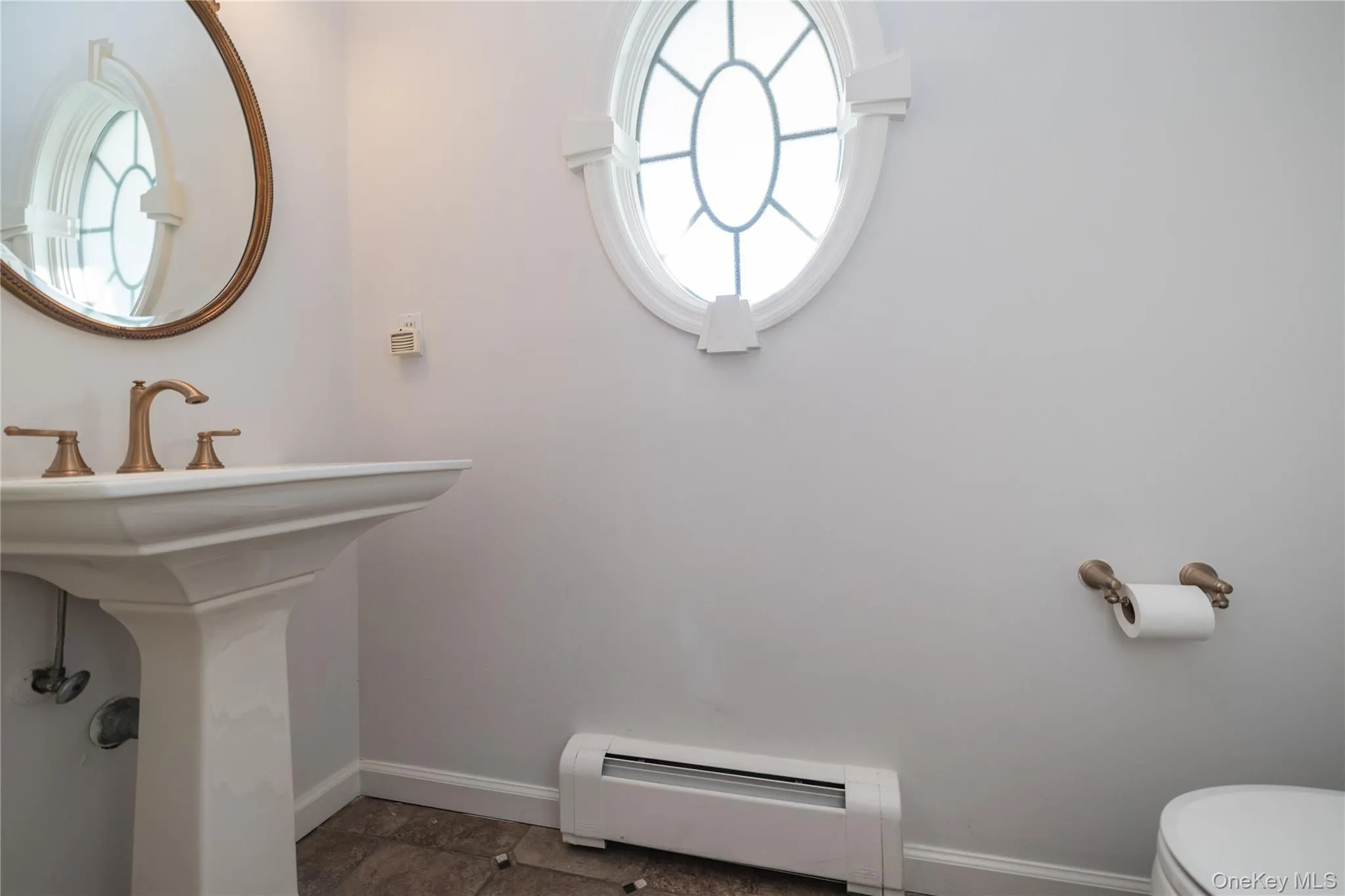 Half bathroom featuring a wealth of natural light, a baseboard radiator, toilet, and baseboards Half bathroom featuring a wealth of natural light, a baseboard radiator, toilet, and baseboards