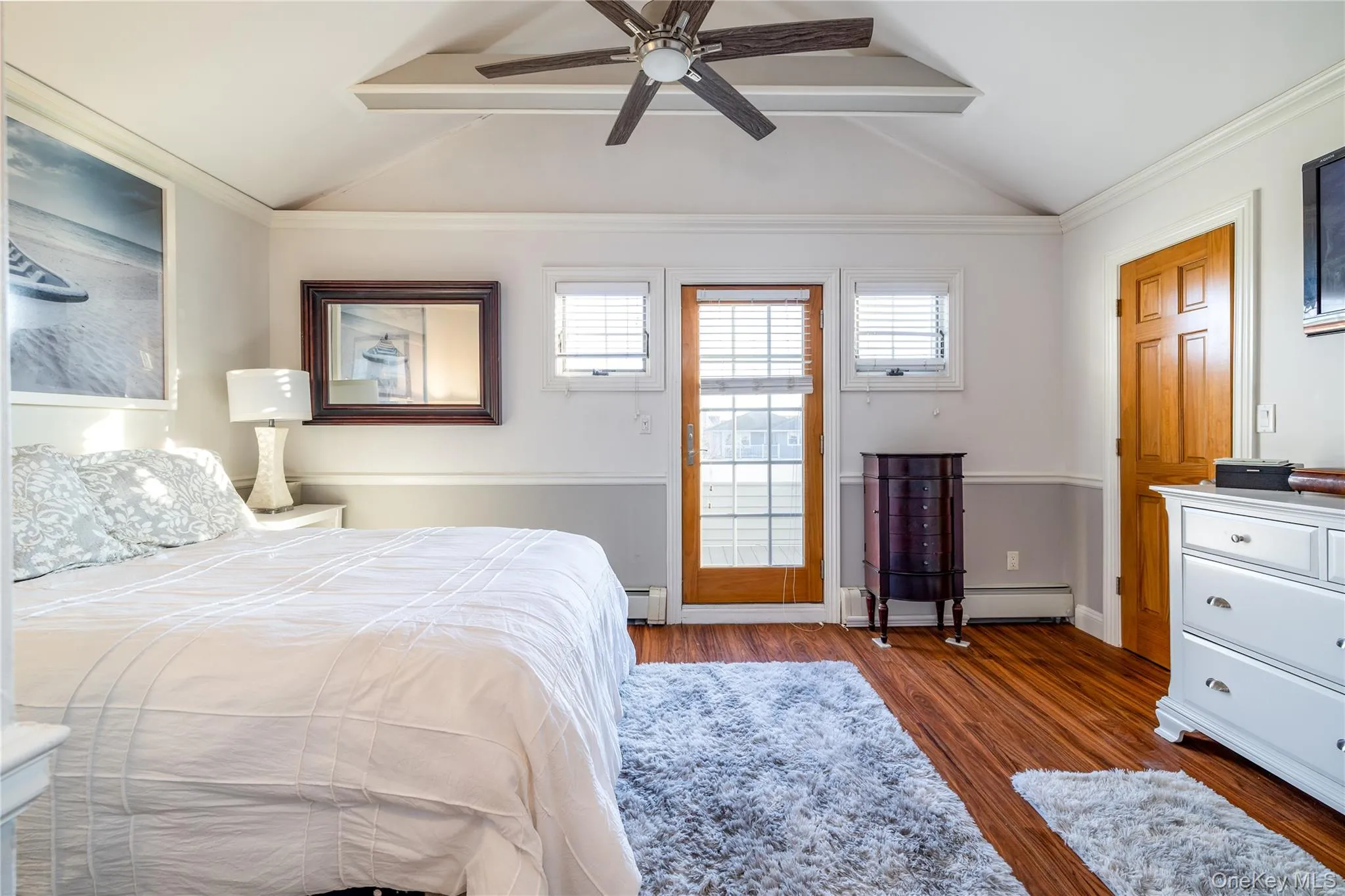 Bedroom featuring vaulted ceiling with beams, a baseboard radiator, baseboards, and wood finished floors Bedroom featuring vaulted ceiling with beams, a baseboard radiator, baseboards, and wood finished floors