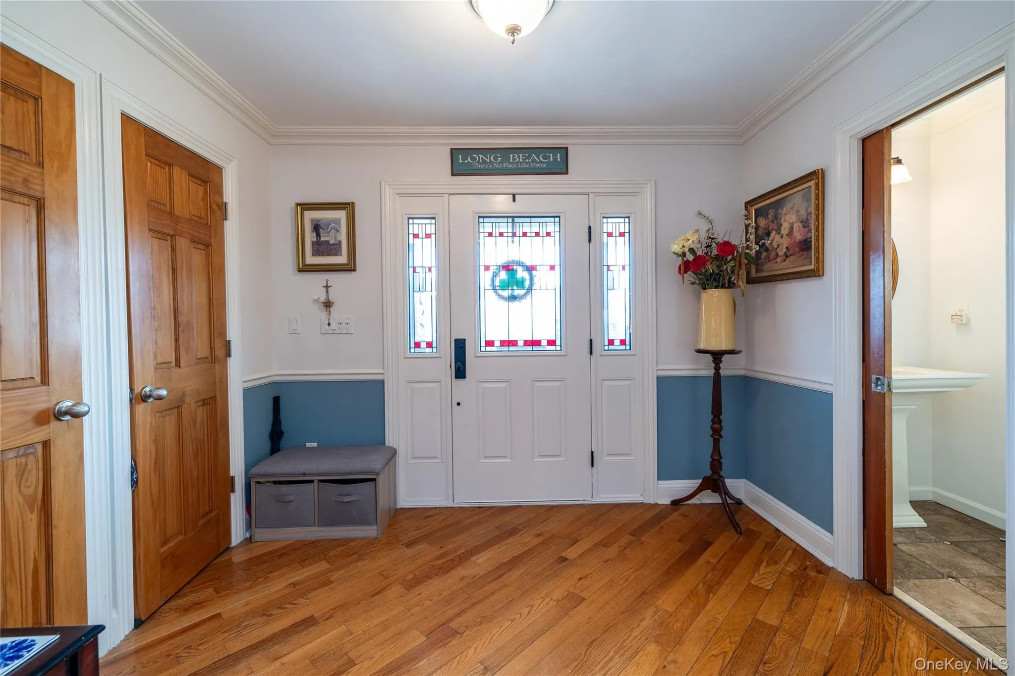 Entryway featuring light wood-style floors, ornamental molding, and baseboards Entryway featuring light wood-style floors, ornamental molding, and baseboards