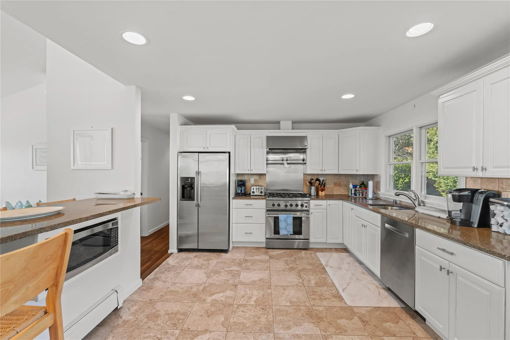 Spacious Chefs Kitchen with appliances with stainless steel finishes, backsplash, a sink, and white cabinetry Spacious Chefs Kitchen with appliances with stainless steel finishes, backsplash, a sink, and white cabinetry