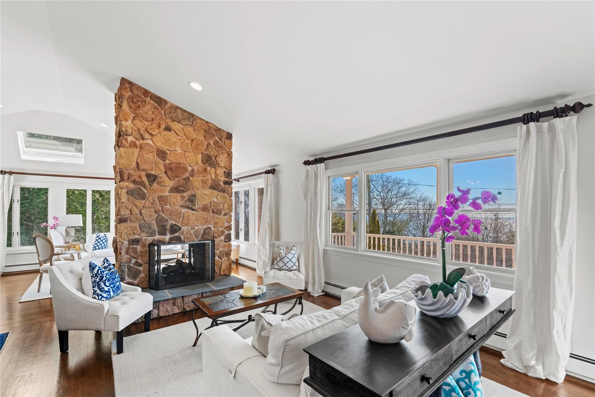 Open Living area featuring lofted ceiling, Bay views, wood finished floors, and a stone fireplace Open Living area featuring lofted ceiling, Bay views, wood finished floors, and a stone fireplace