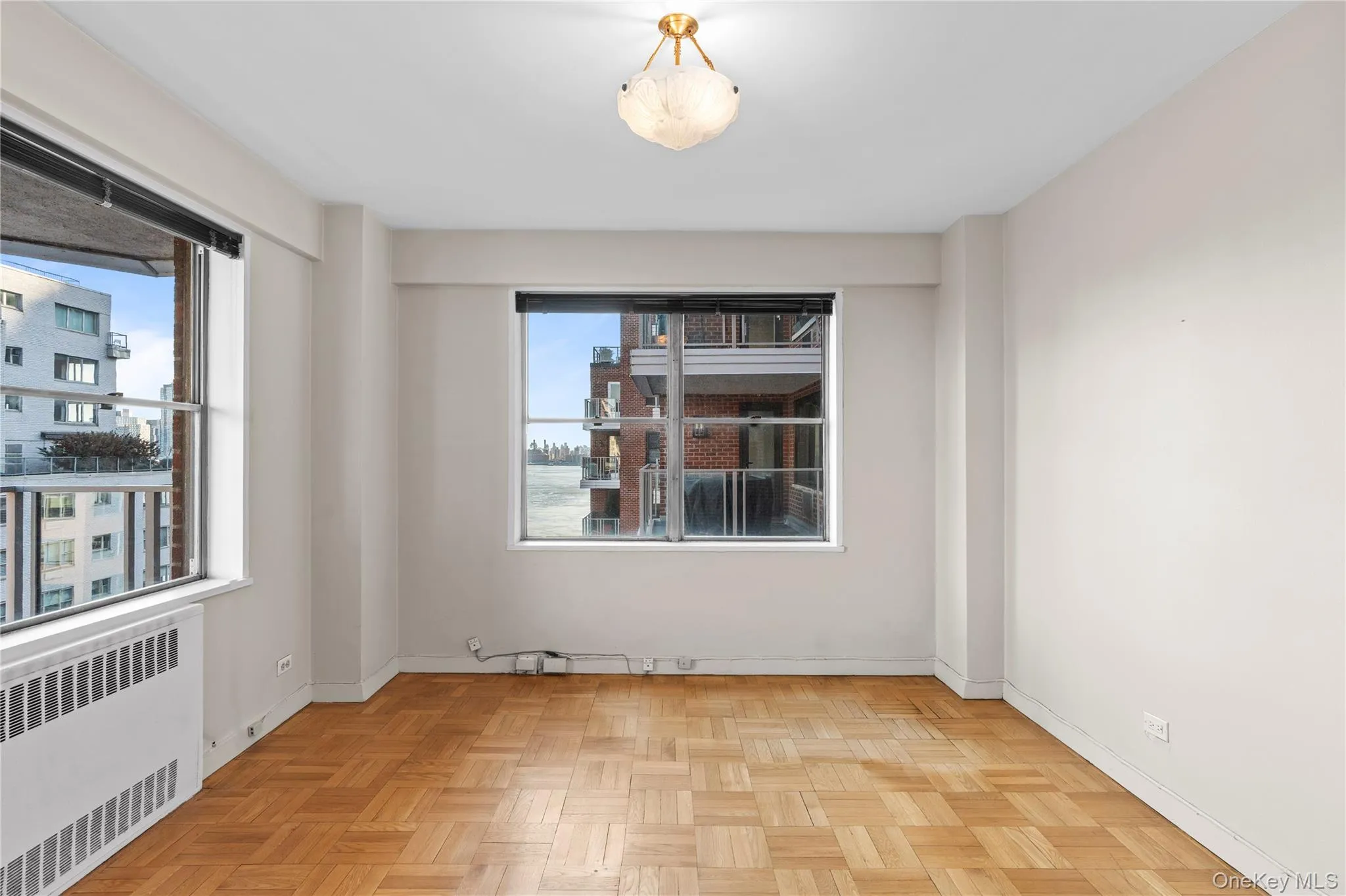 Unfurnished room featuring a healthy amount of sunlight, radiator, and baseboards Unfurnished room featuring a healthy amount of sunlight, radiator, and baseboards