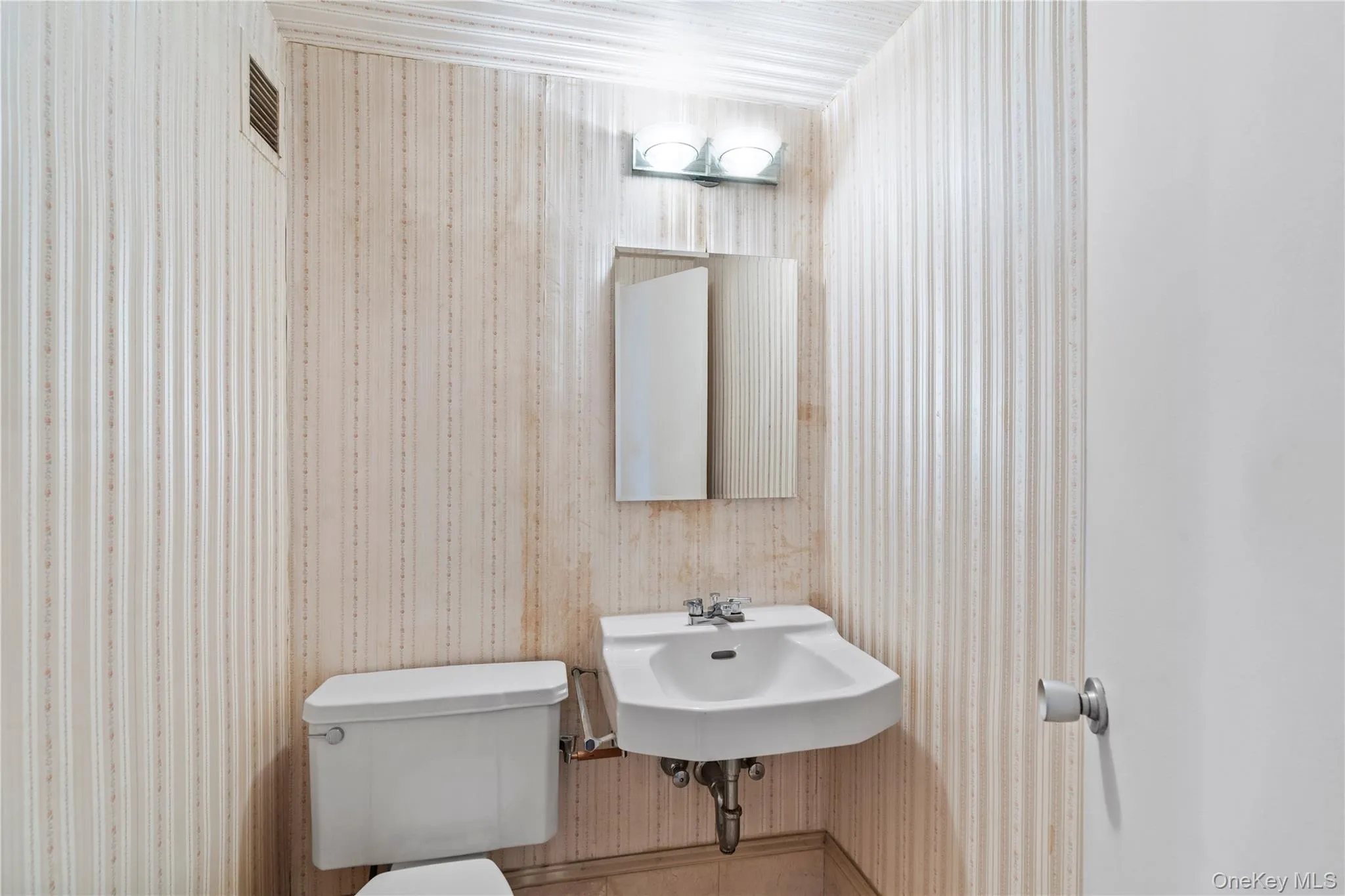 Half bathroom with a sink, visible vents, and toilet Half bathroom with a sink, visible vents, and toilet